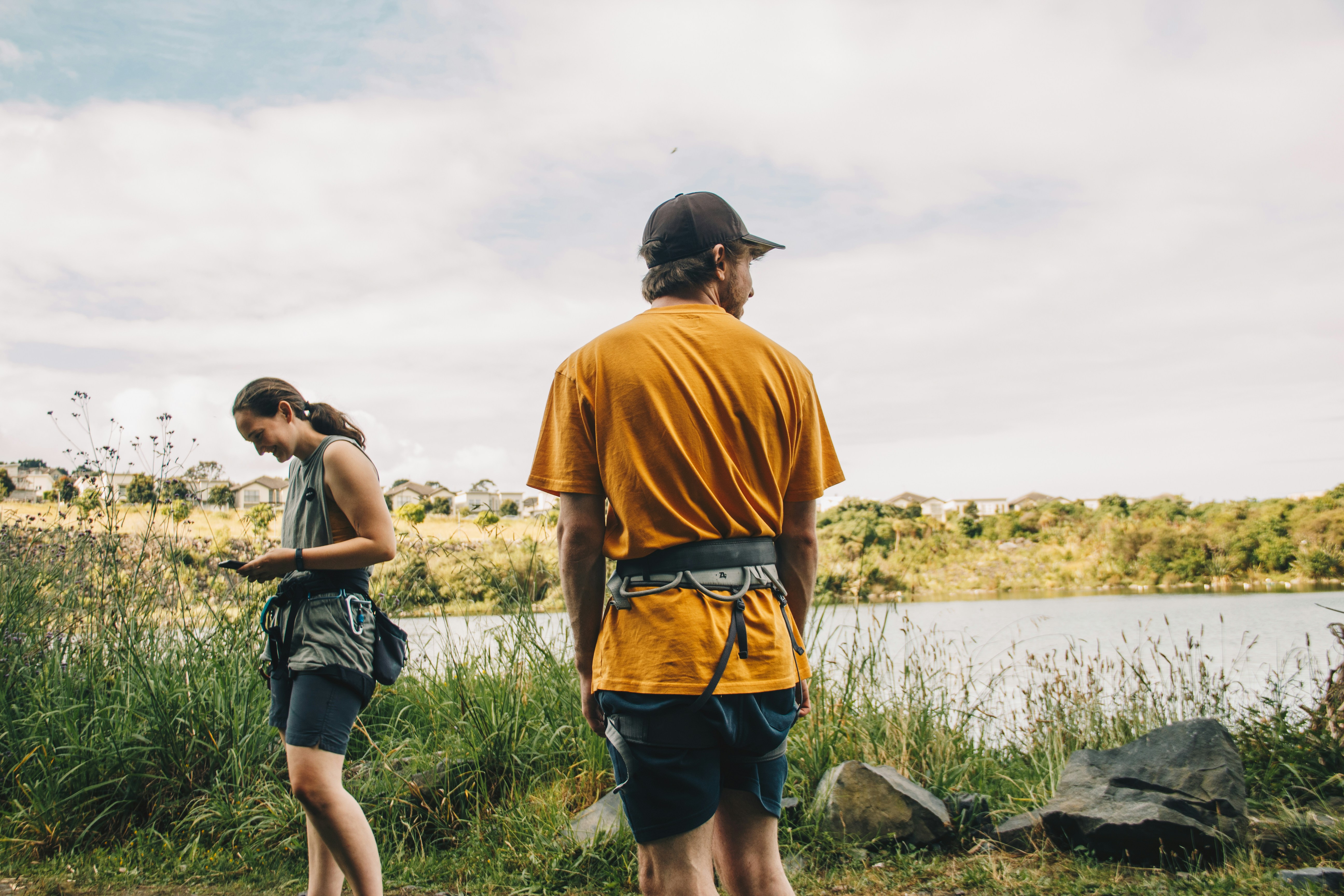 Two people standing near a body of water outdoors.