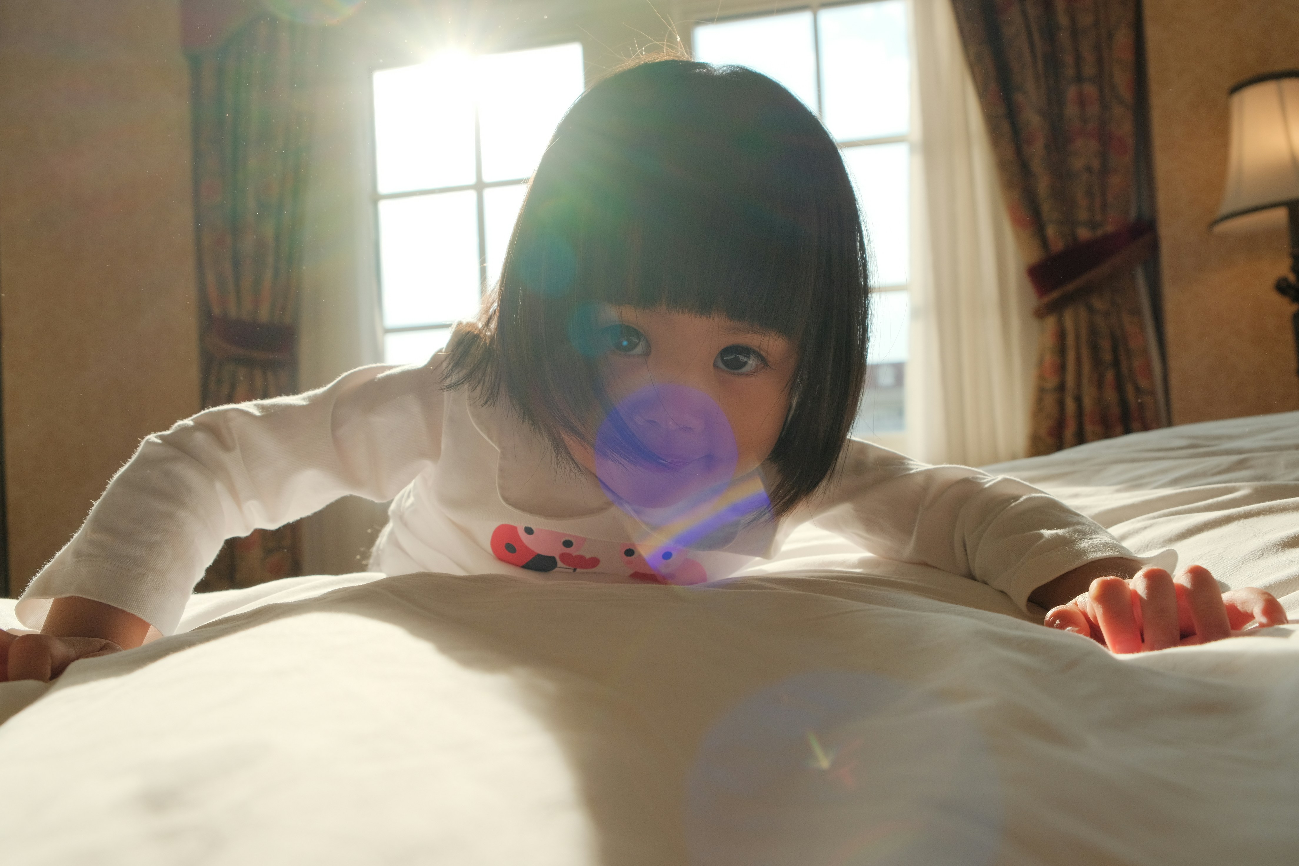 A young child crawls on a bed towards the camera.
