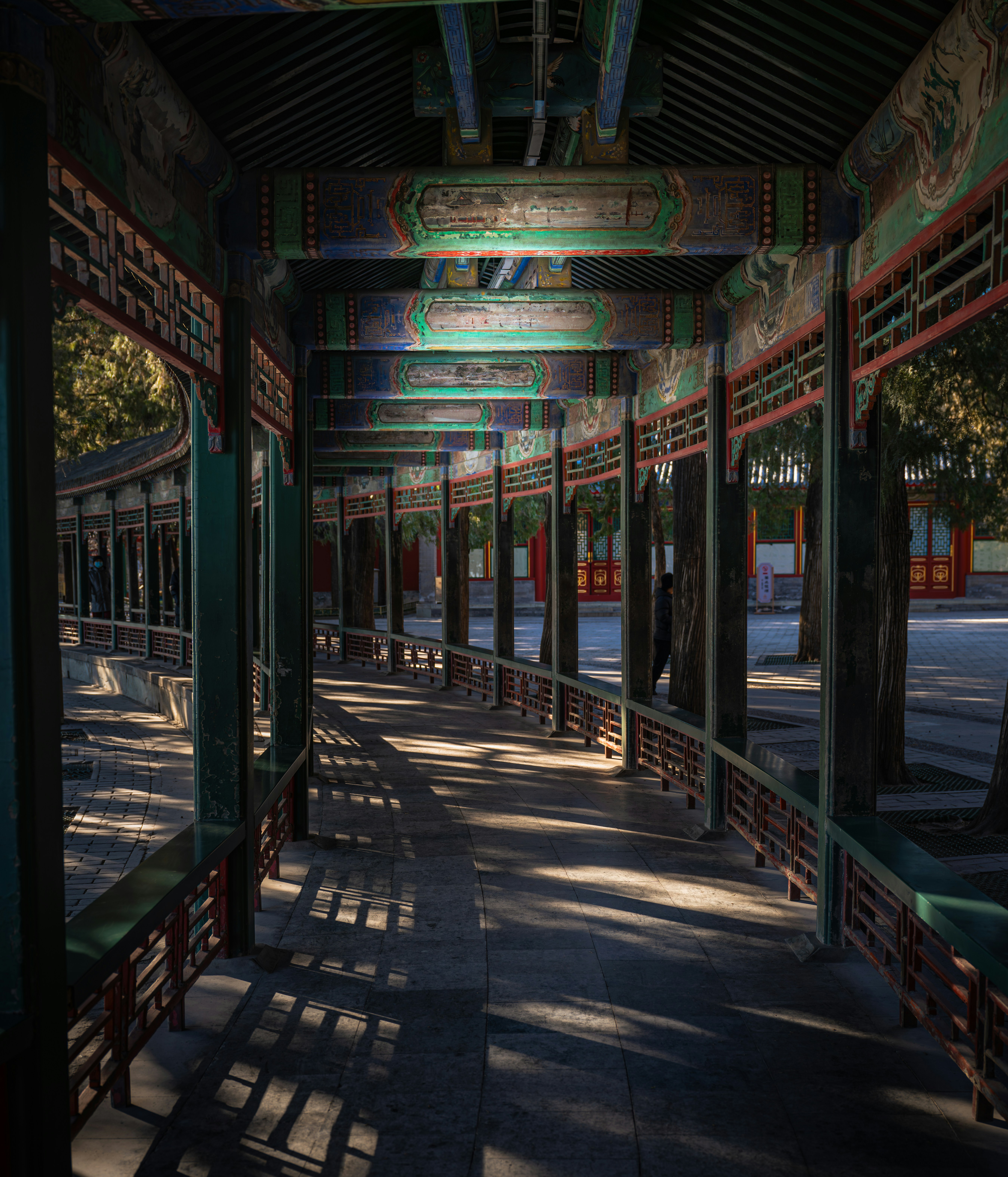 Allée couverte ornée de poutres peintes et de balustrades.