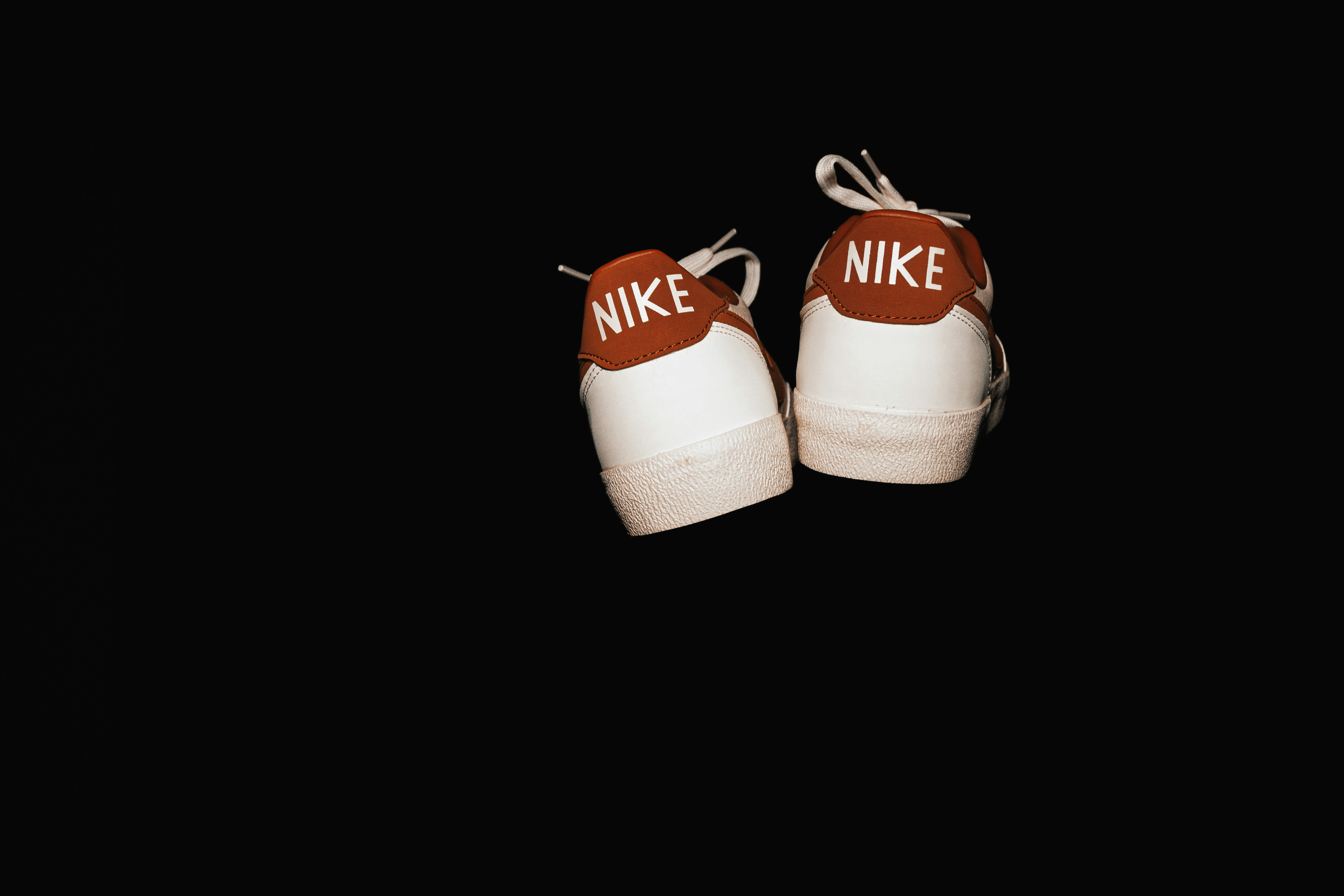 Pair of white nike sneakers on black background