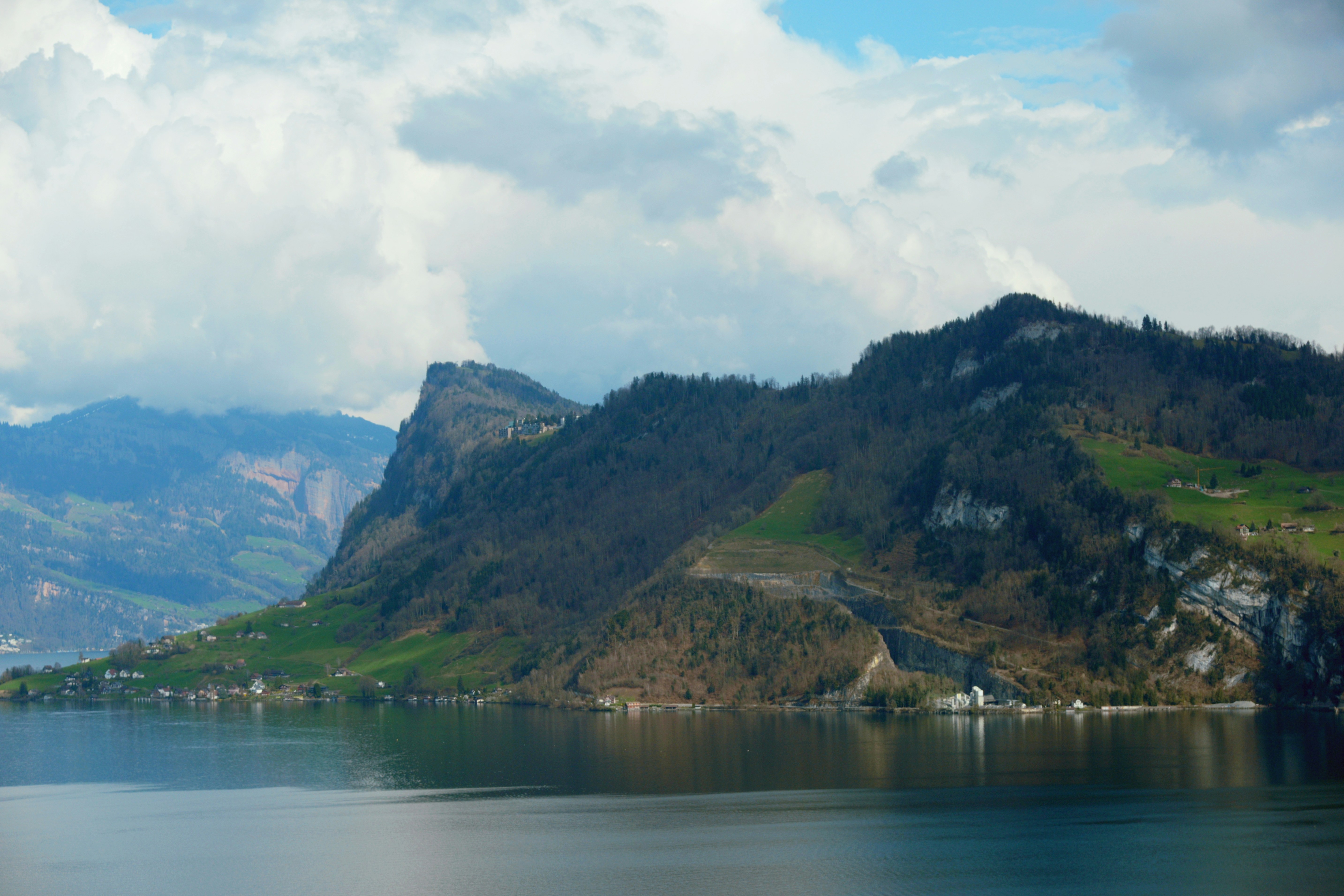 Calm lake with rolling green hills and mountains.