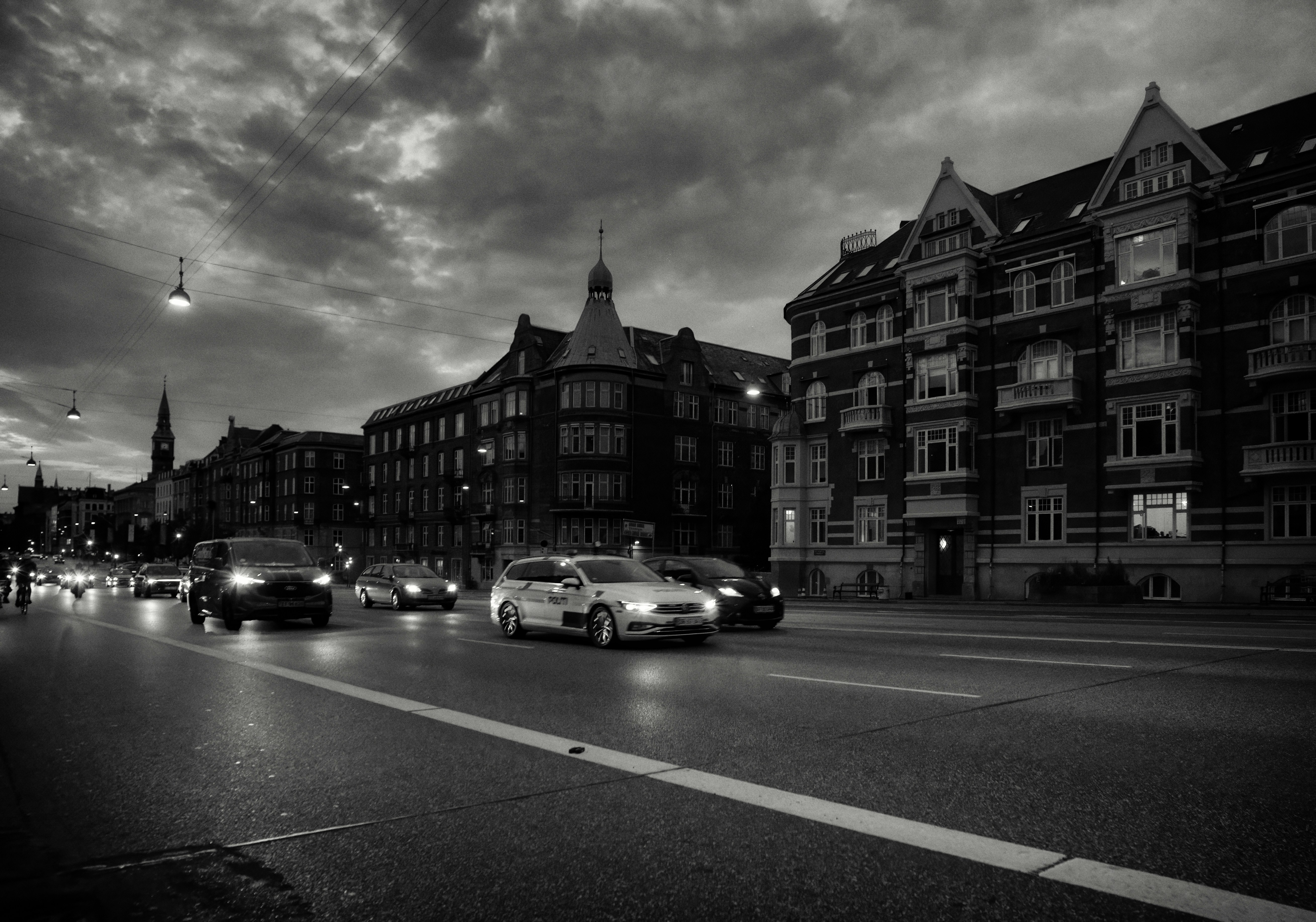 Cars driving on a city street at dusk.