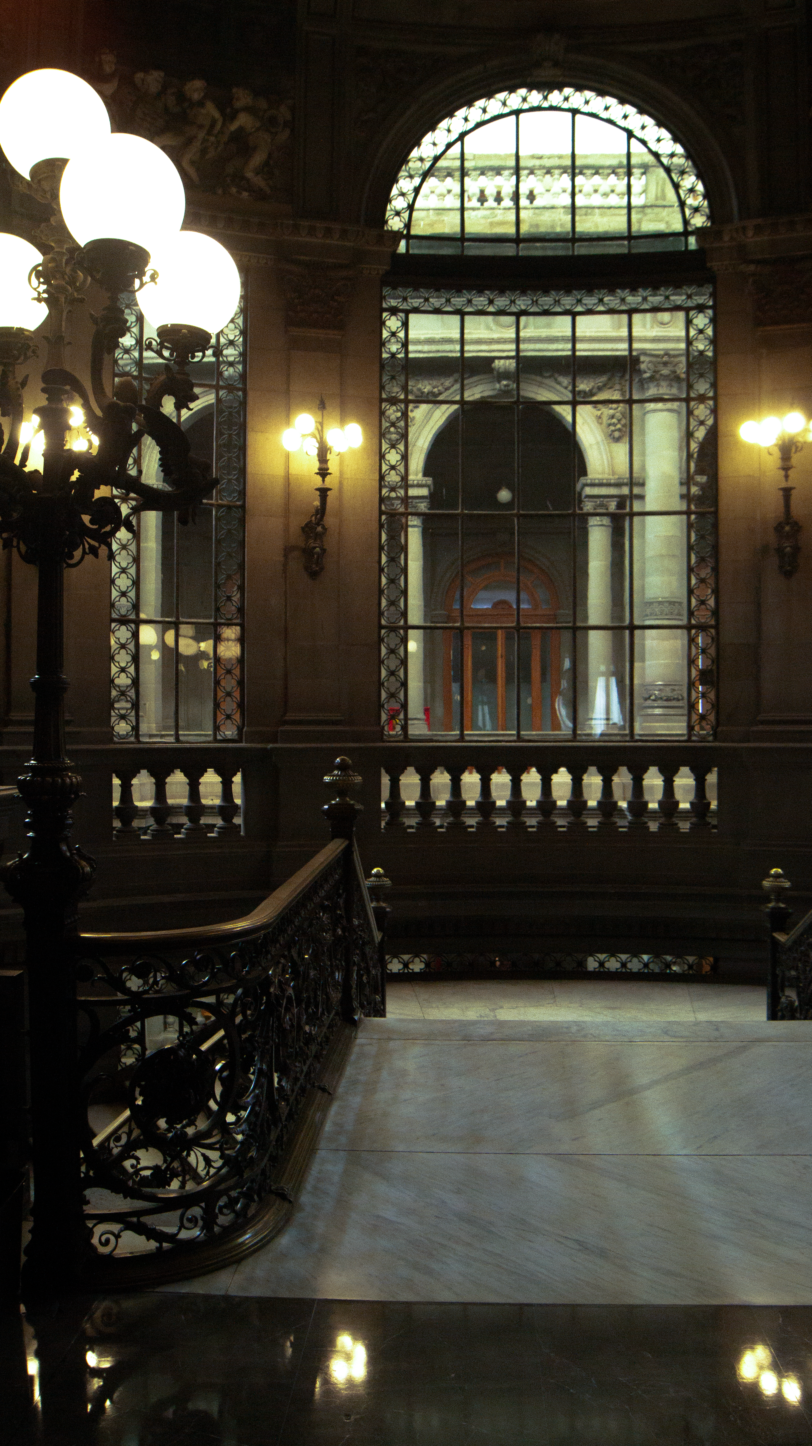 Ornate staircase and grand window in a dimly lit building