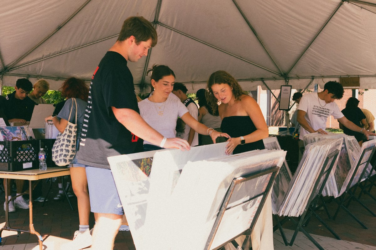 People viewing artwork under a tent at a nonprofit volunteer event