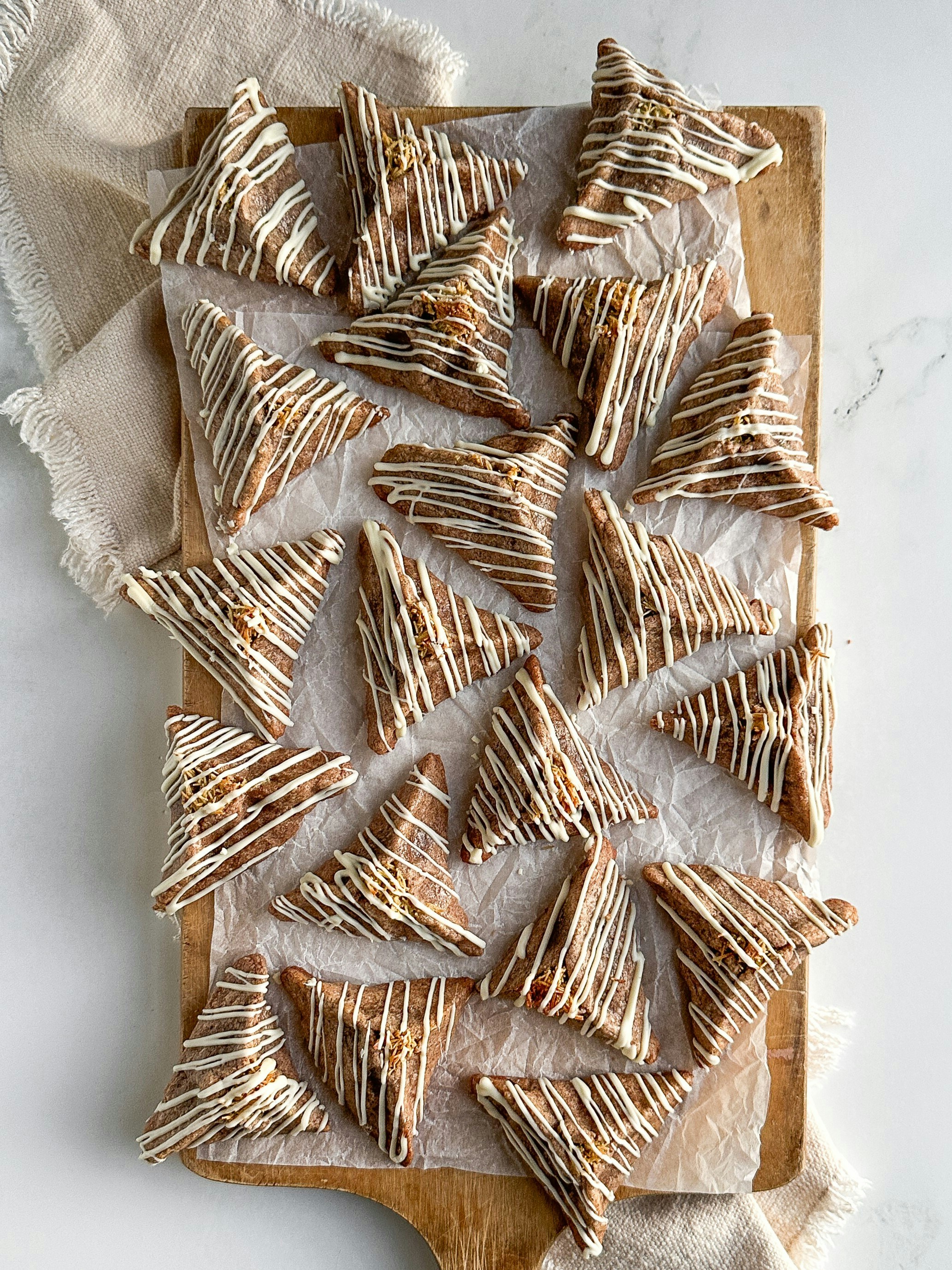 Dreieckige Kekse mit weißem Zuckerguss auf einem Brett beträufelt