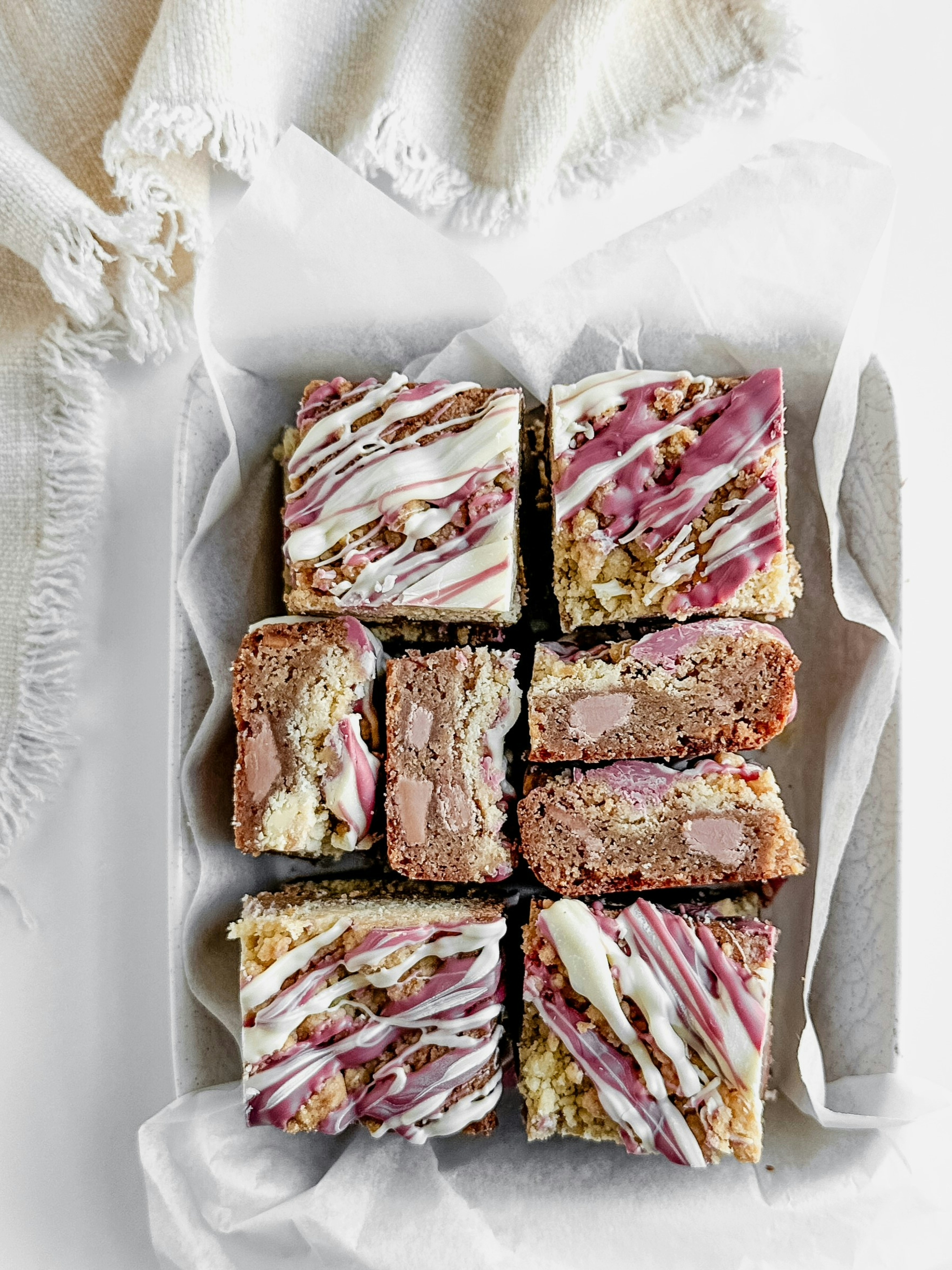 Ruby chocolate blondies in a parchment lined dish with a white linen napkin