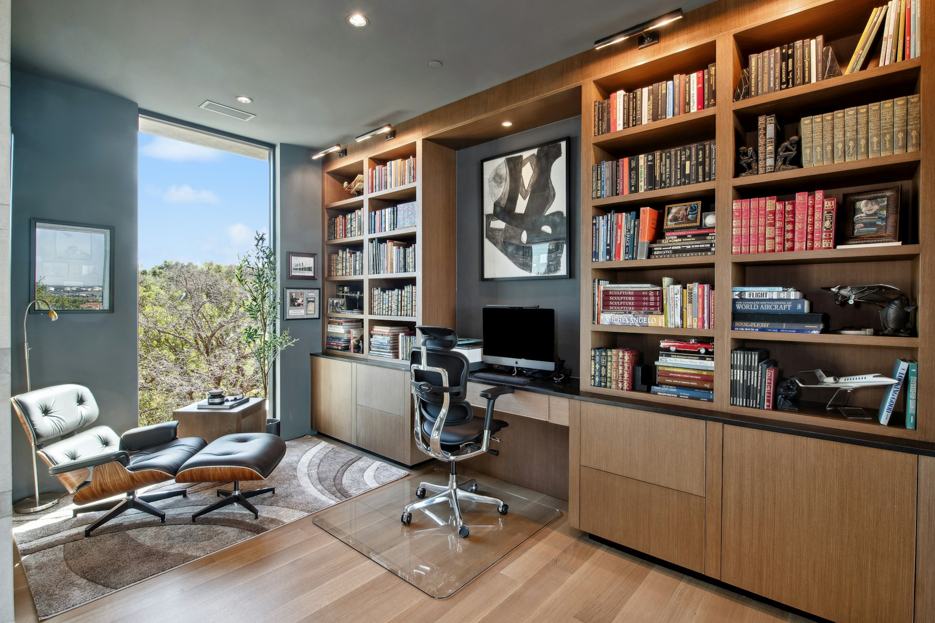 Modern home office with large bookshelves and desk.