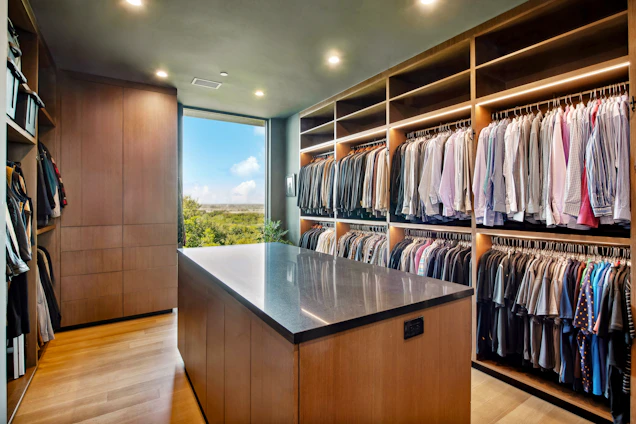 Luxurious walk-in closet with island and abundant clothing storage.