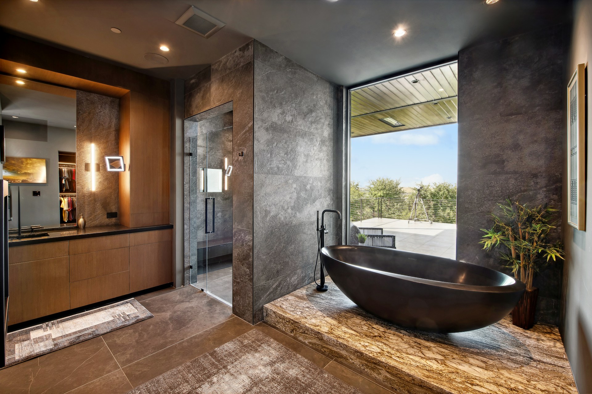 Modern bathroom with stone bathtub and large window.