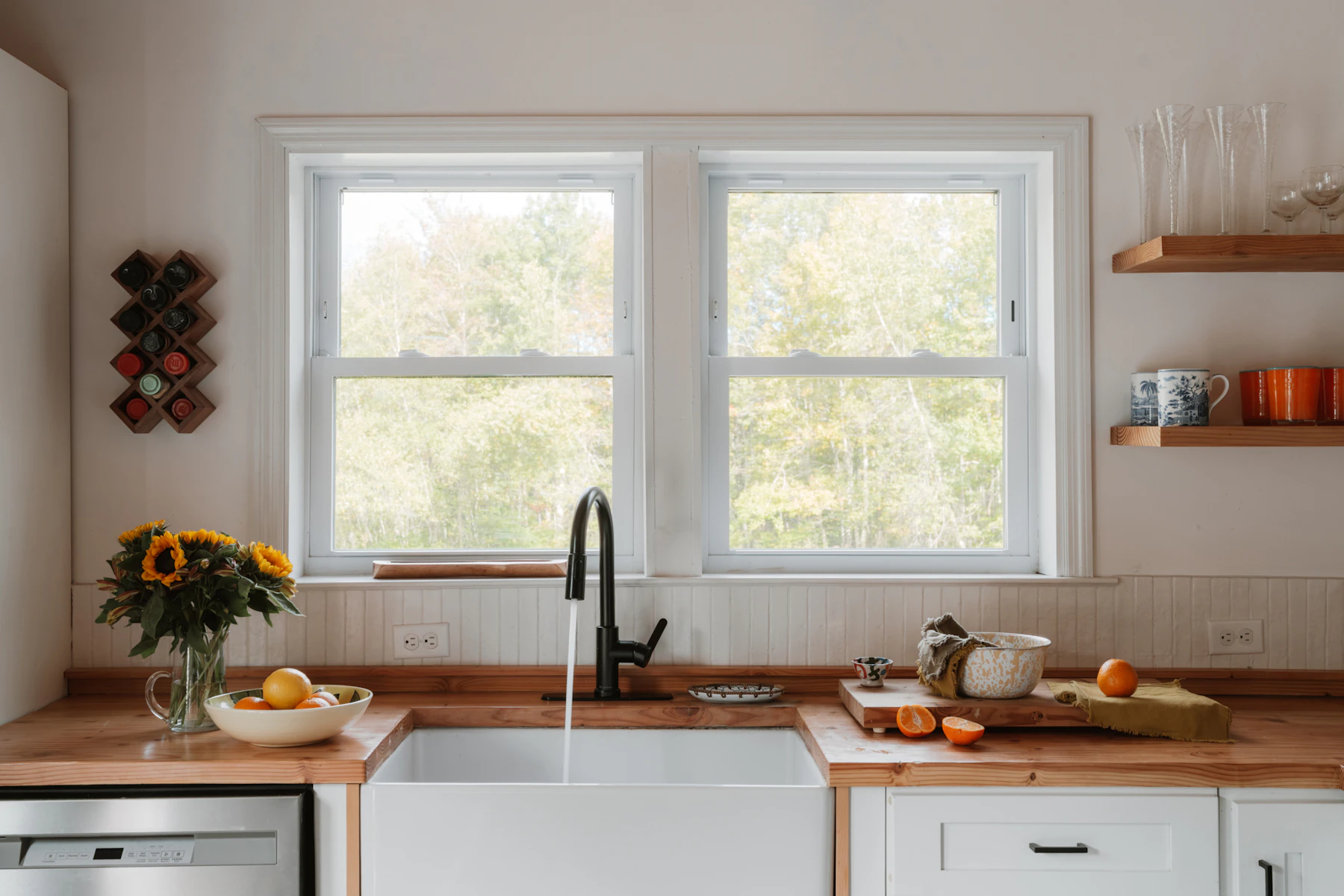 Farmhouse sink area with sunflowers, fruit, wood worktop and everyday kitchen objects