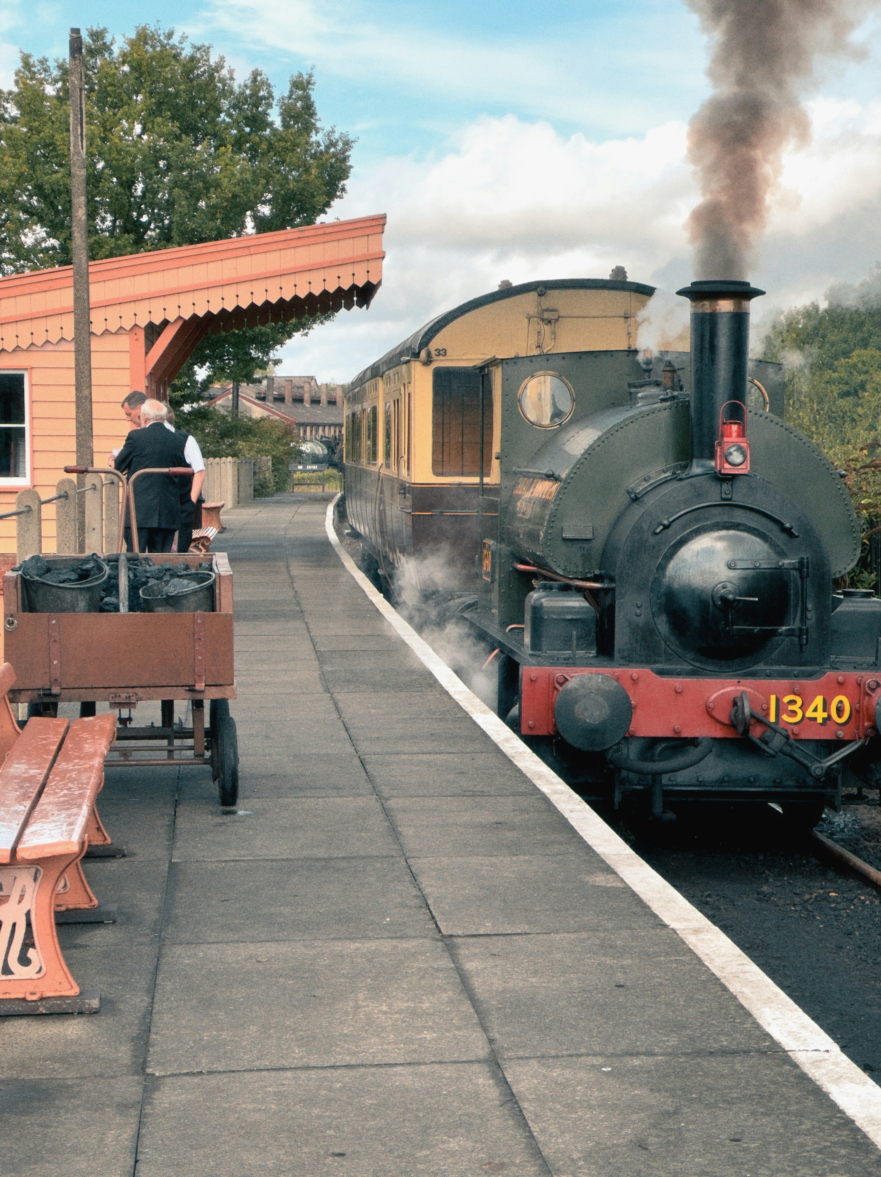 Steam train at a station with a station master.