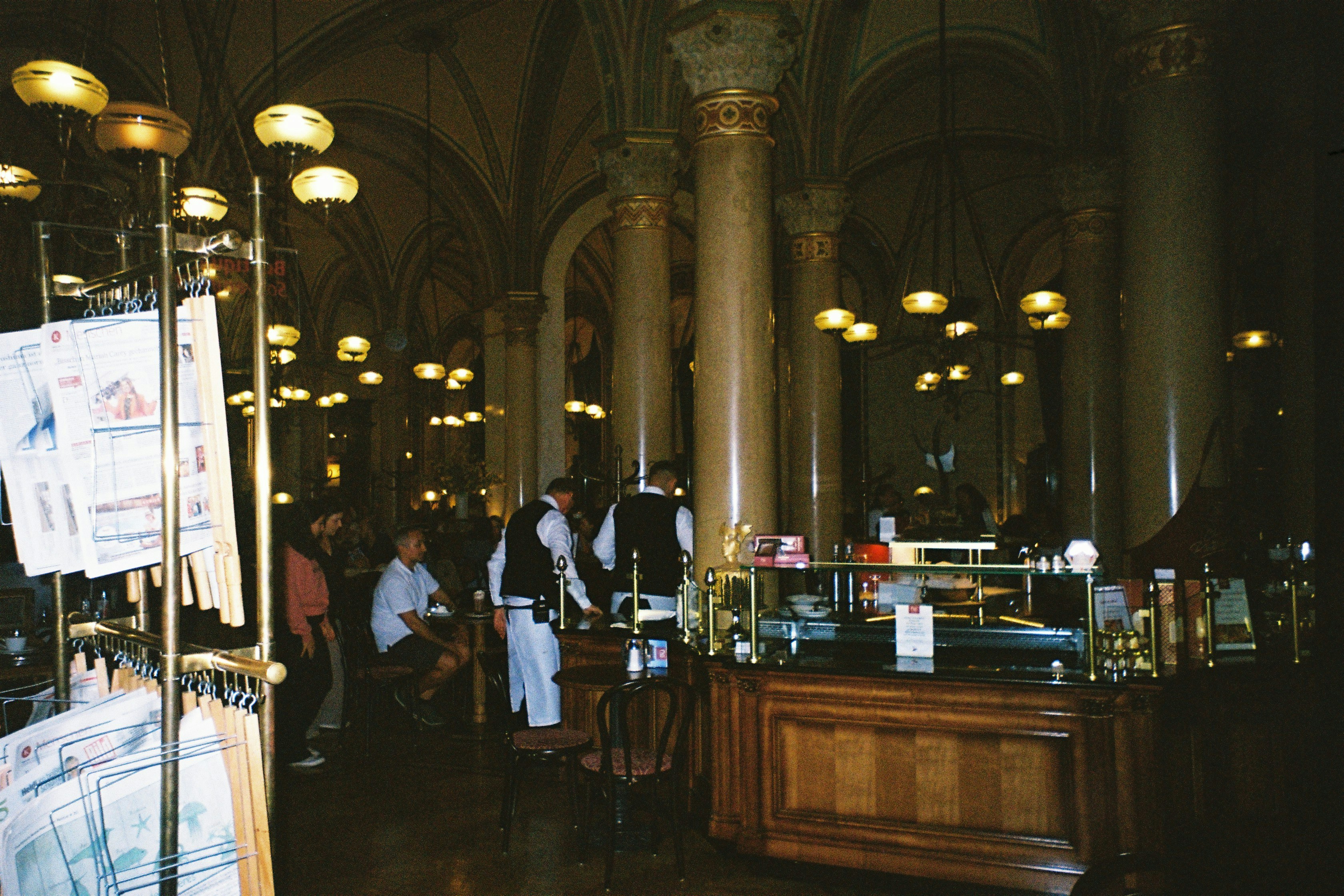 People in a dimly lit ornate cafe with columns