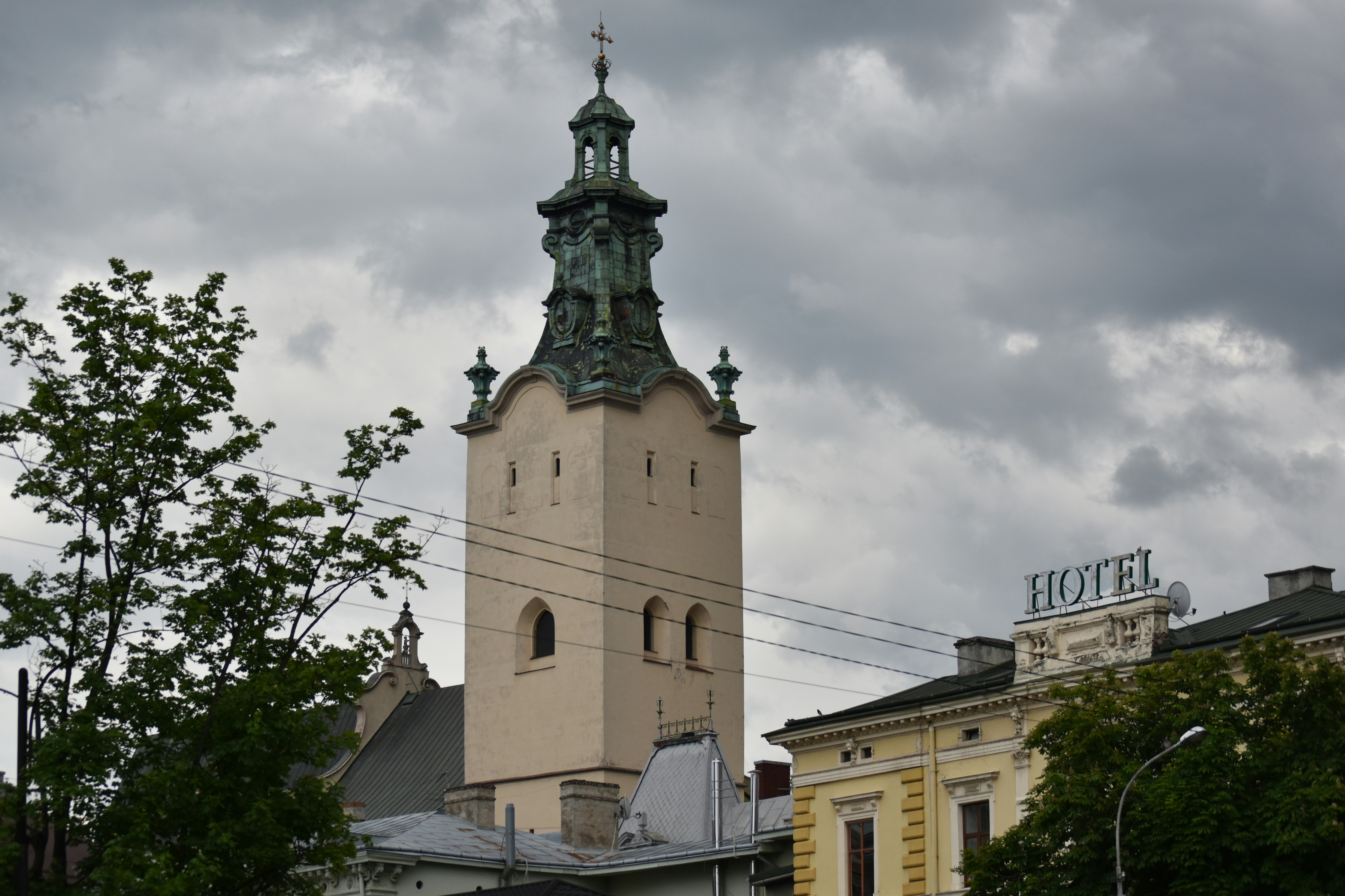 Tall church tower with a hotel sign nearby.