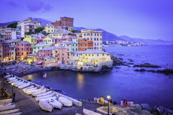 Colorful buildings line a harbor with boats at dusk.