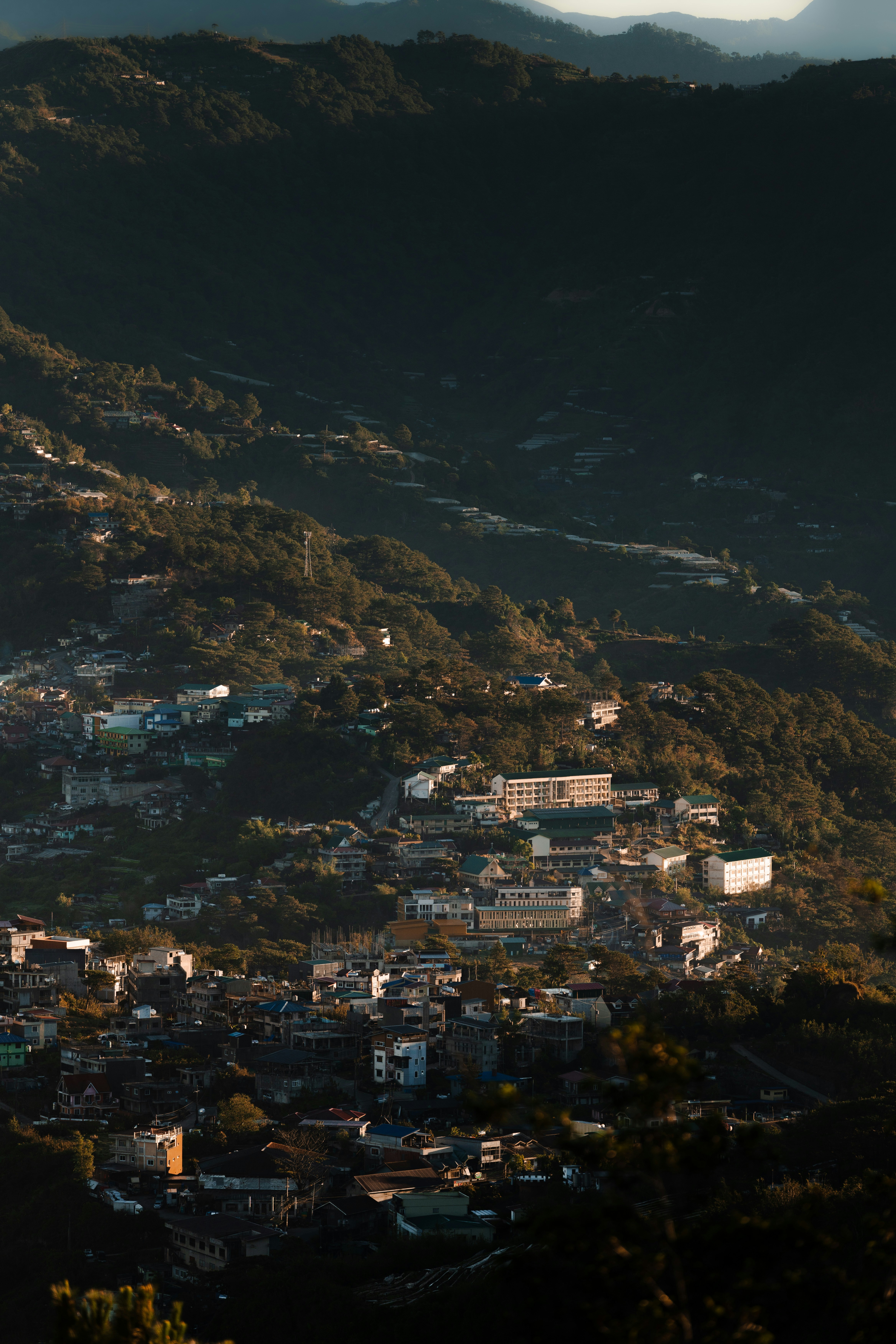 Sunlit town nestled in lush green mountainside.