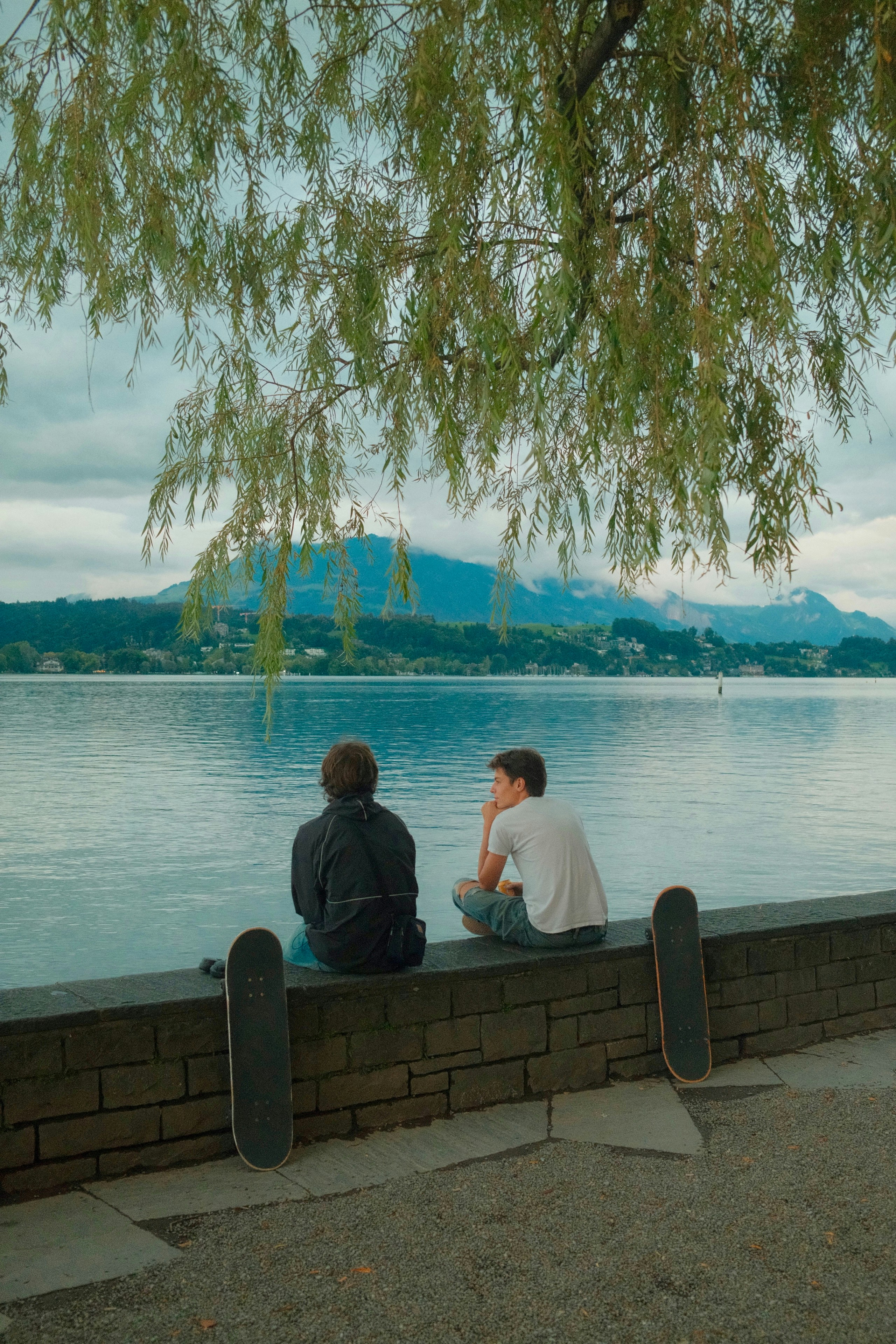Deux amis sont assis au bord d’un lac avec des planches à roulettes.