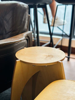 Modern wooden stool next to leather armchair