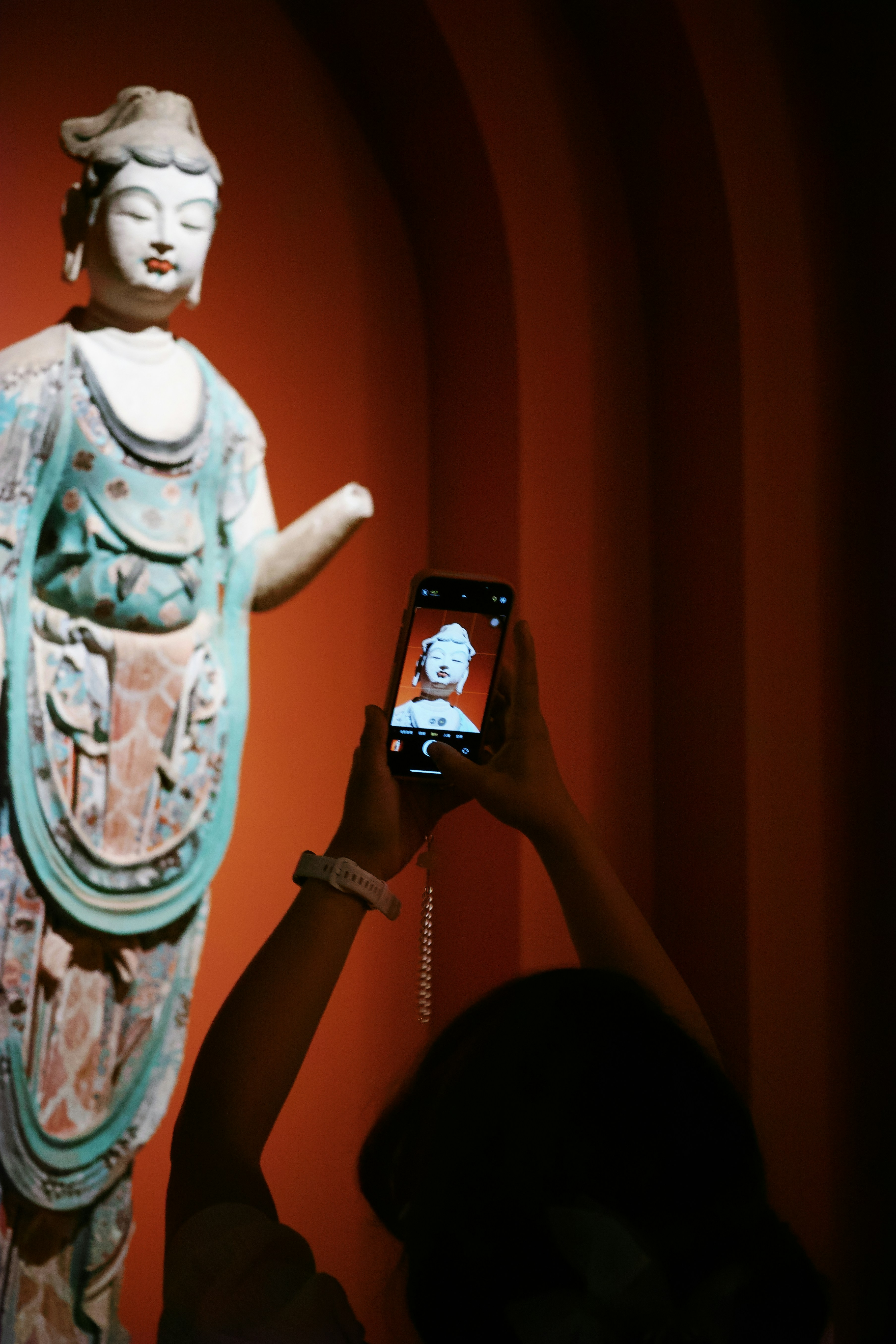 Person taking a picture of a statue with a phone
