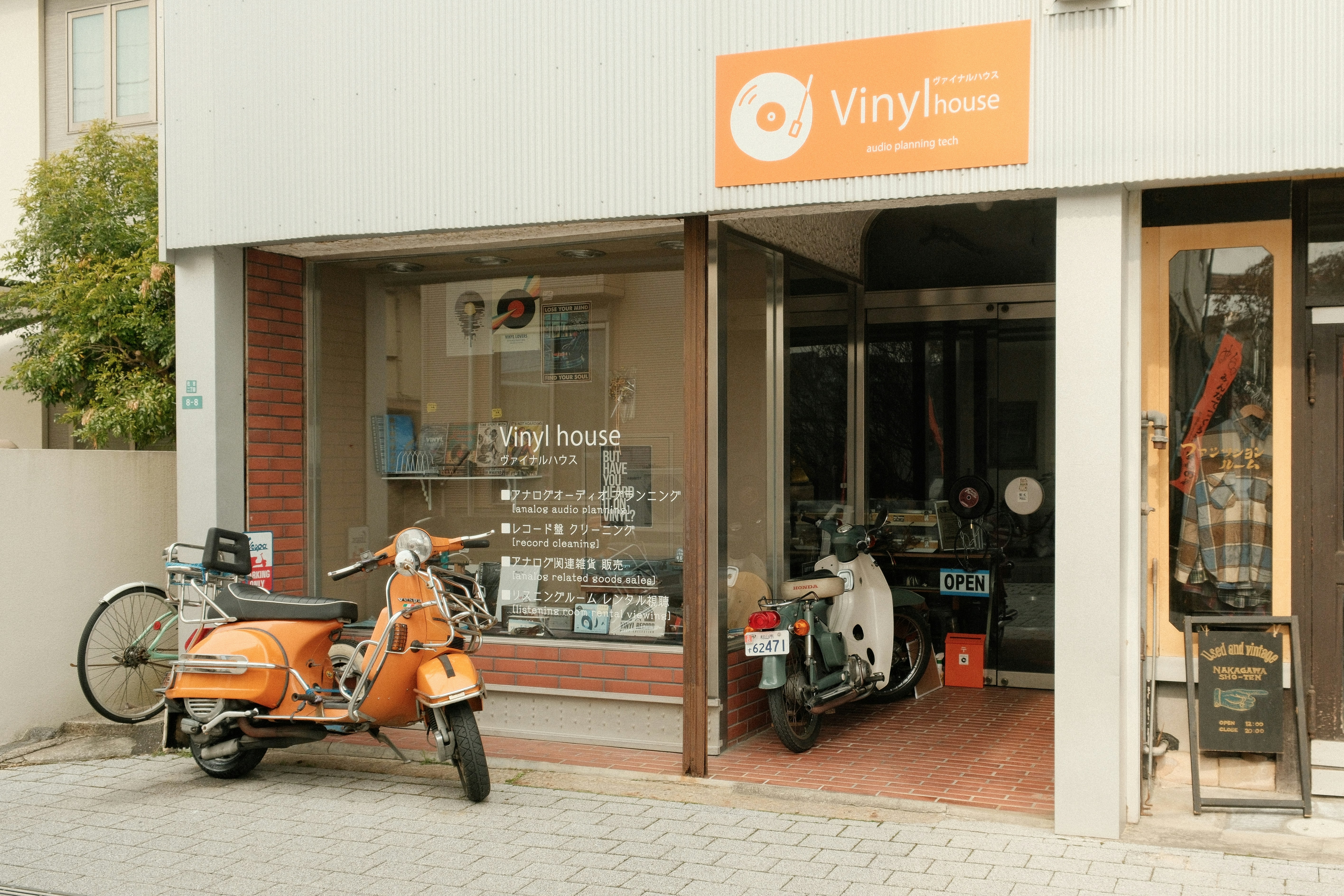 Orange scooters parked outside a record store.