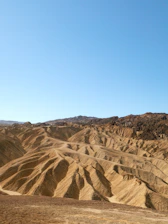 Barren desert landscape with rolling hills under clear sky