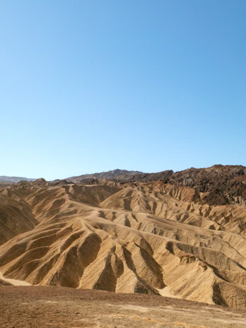 Barren desert landscape with rolling hills under clear sky
