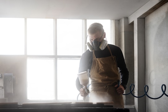 Man wearing respirator and apron working in workshop.