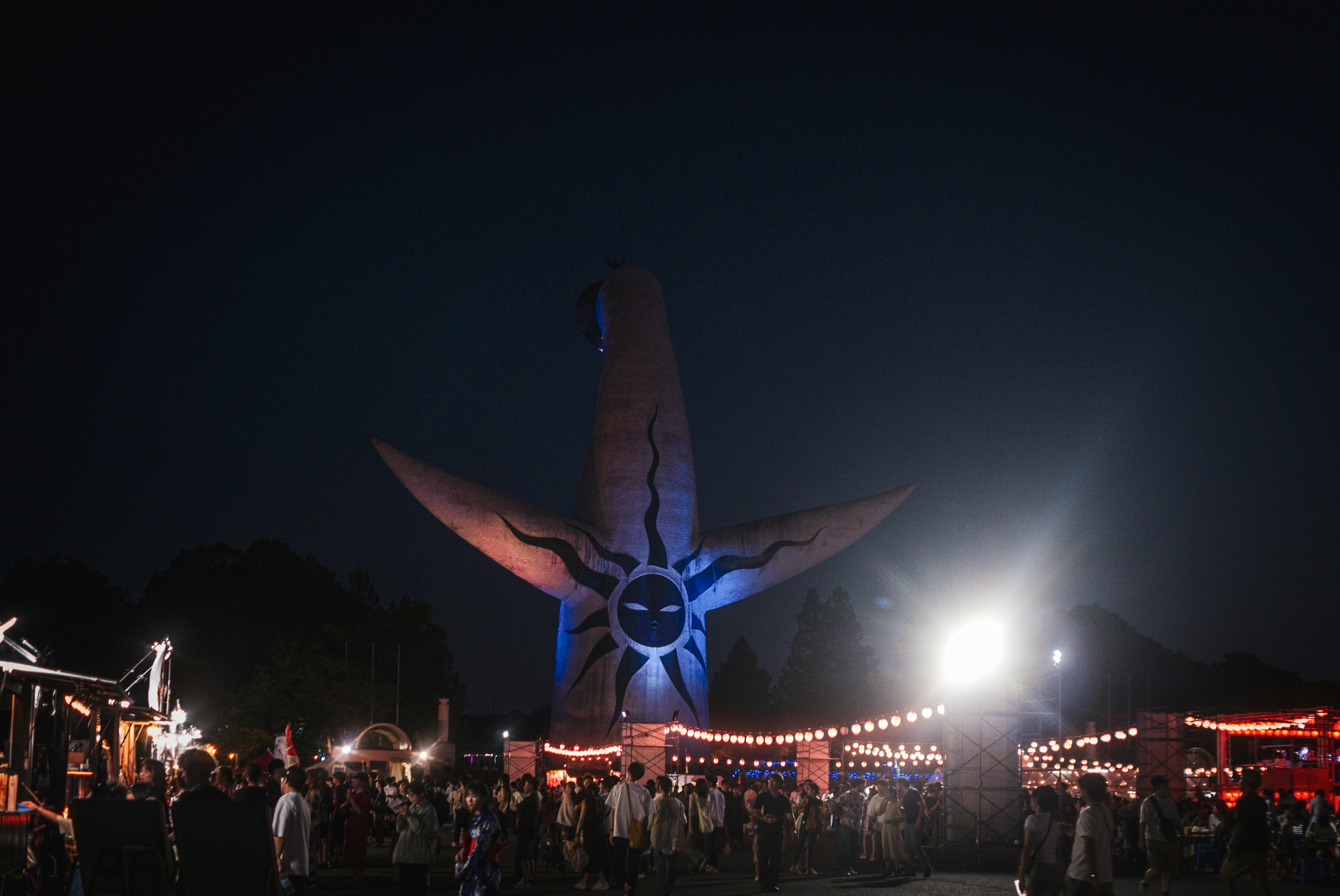 Giant sun sculpture at nighttime festival with crowd