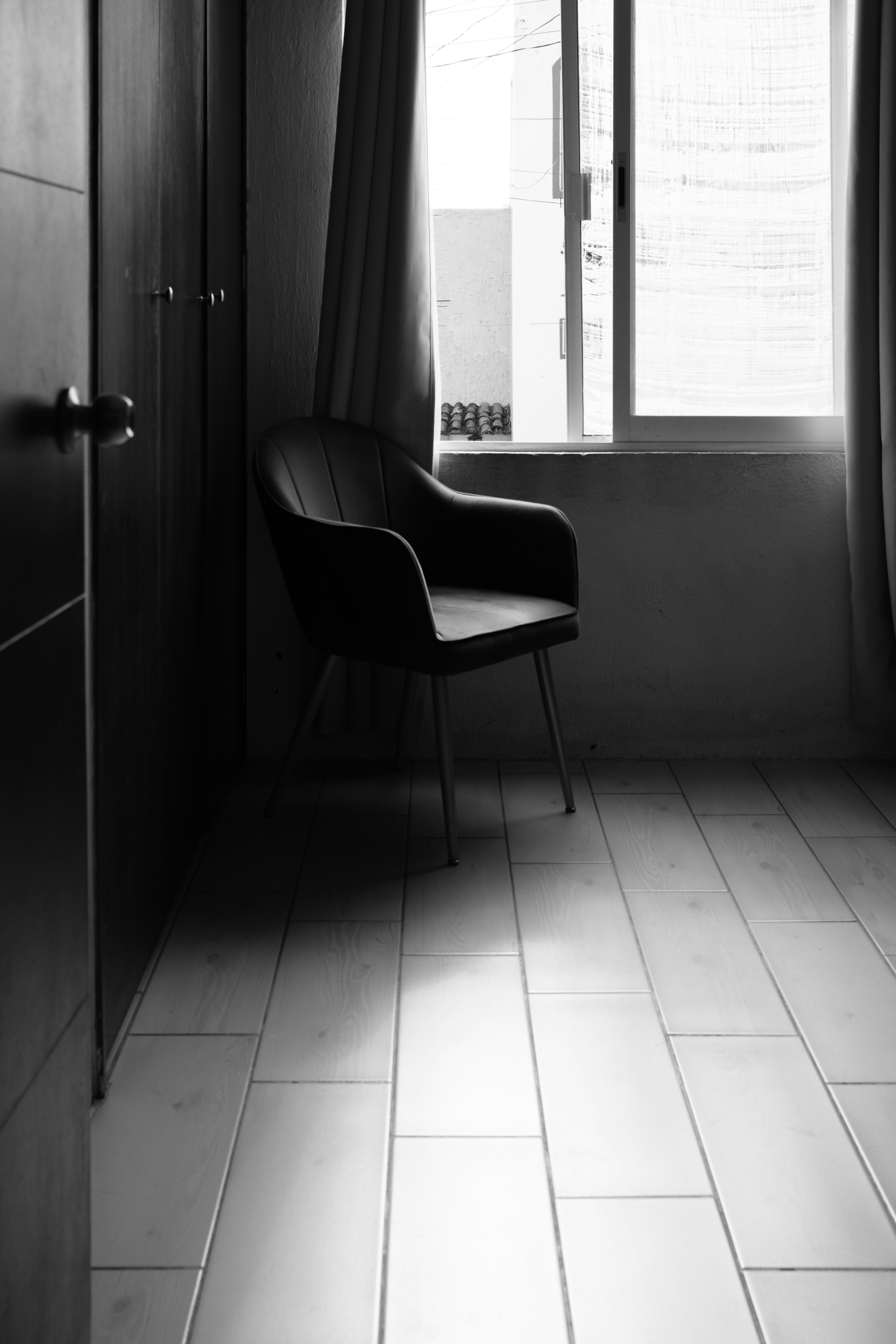 A single chair sits by a sunlit window.