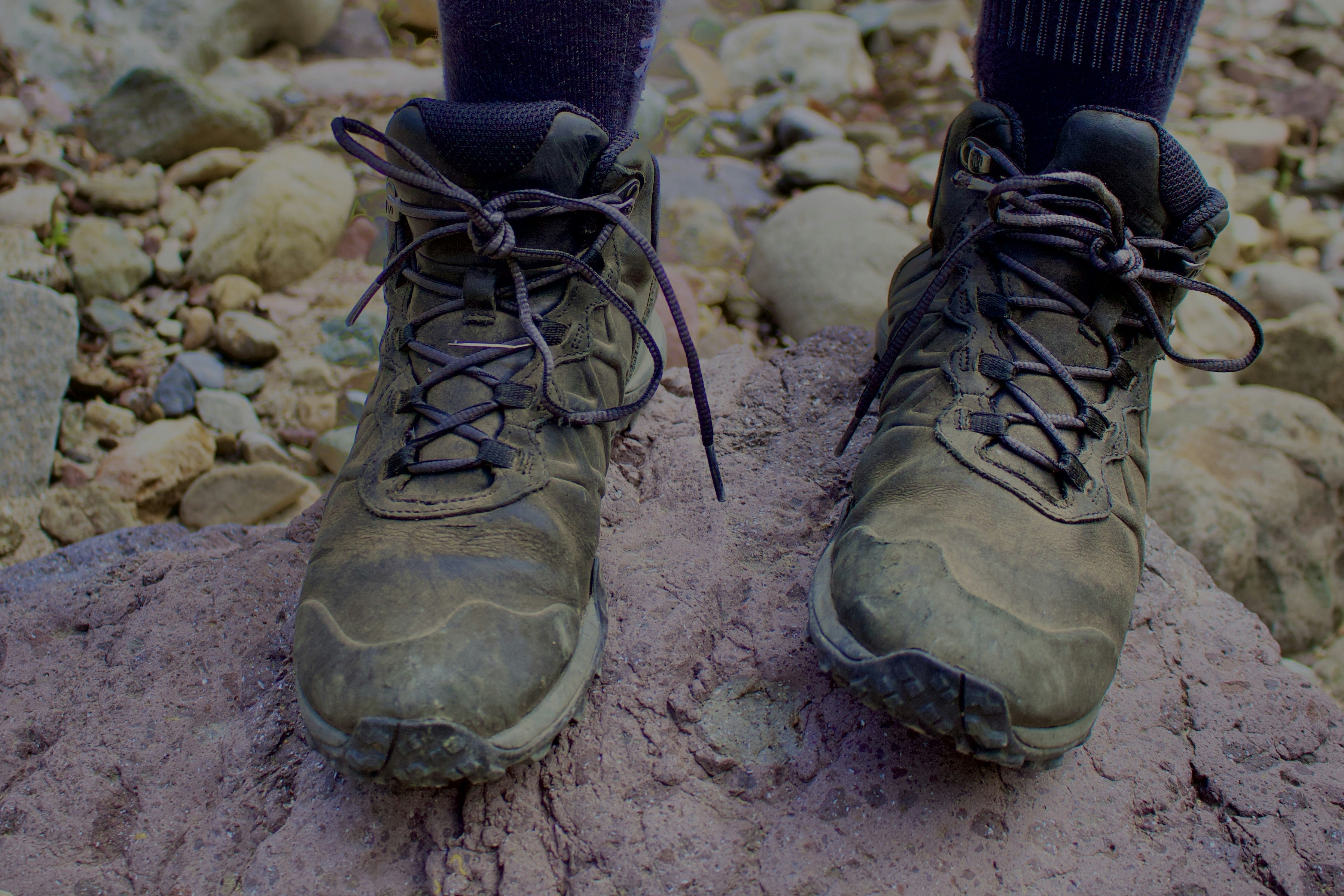 Dirty hiking boots resting on a rock