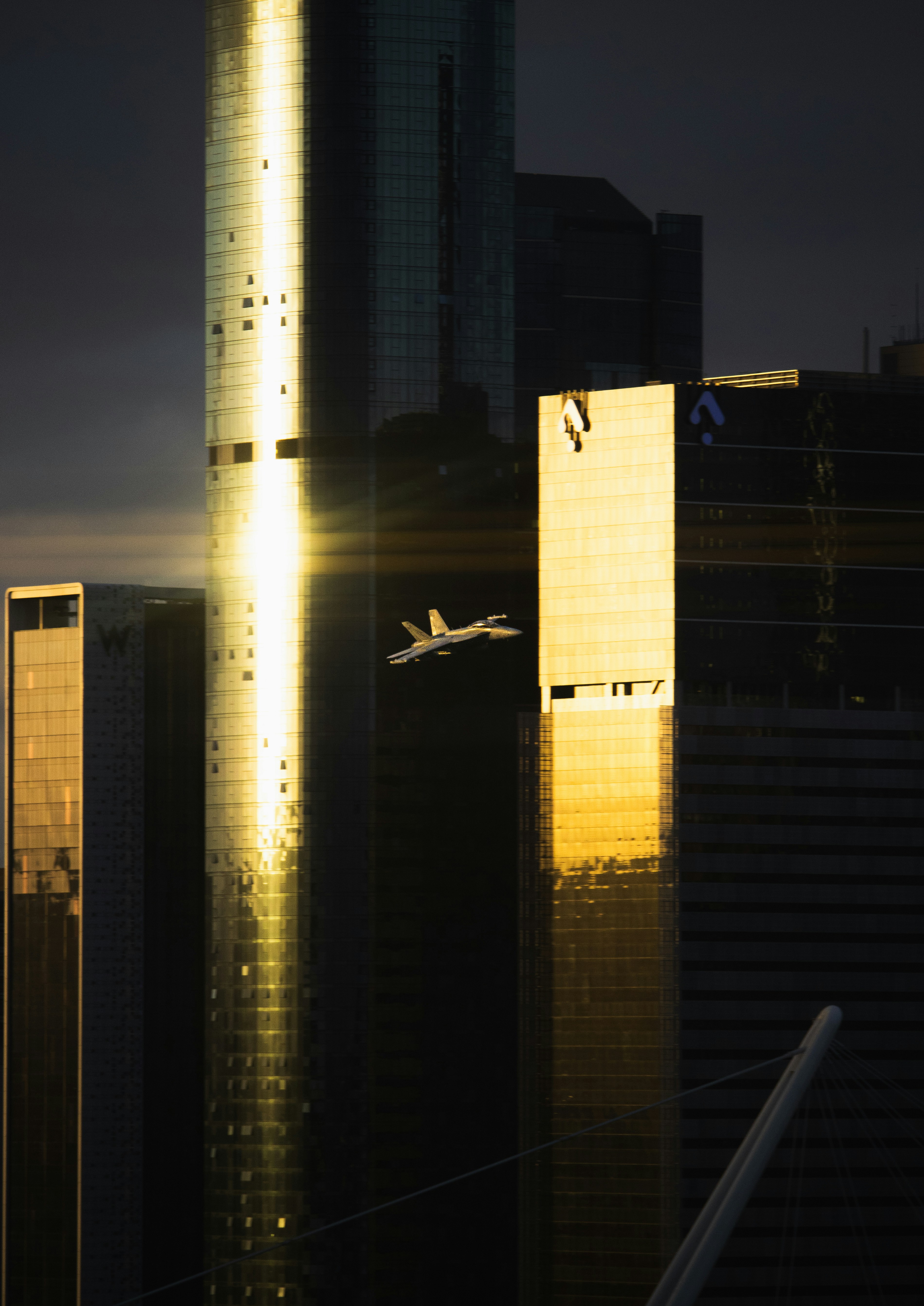 Jet flying past golden skyscrapers at sunset