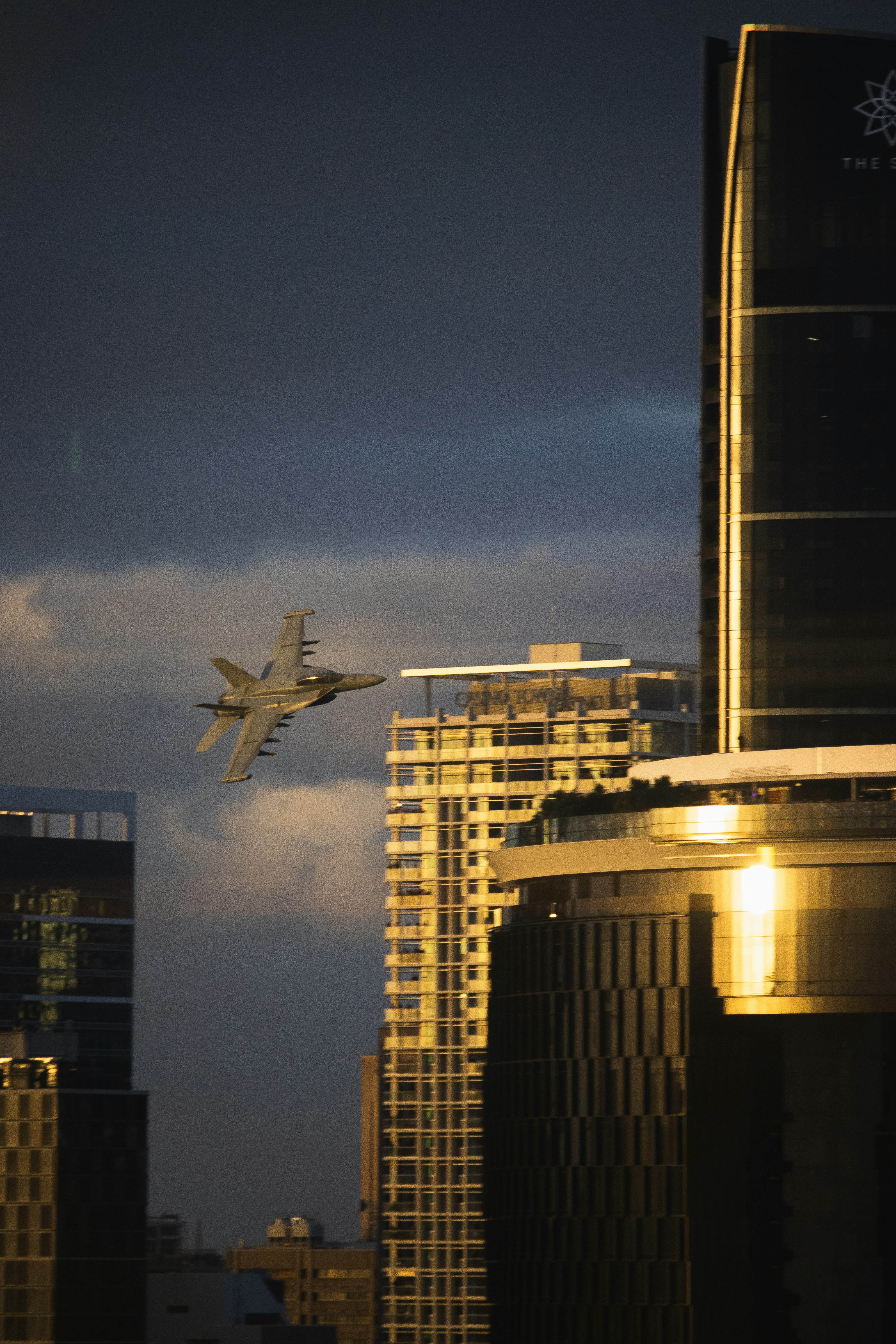 A fighter jet flies between modern city buildings. photo – Free Image ...