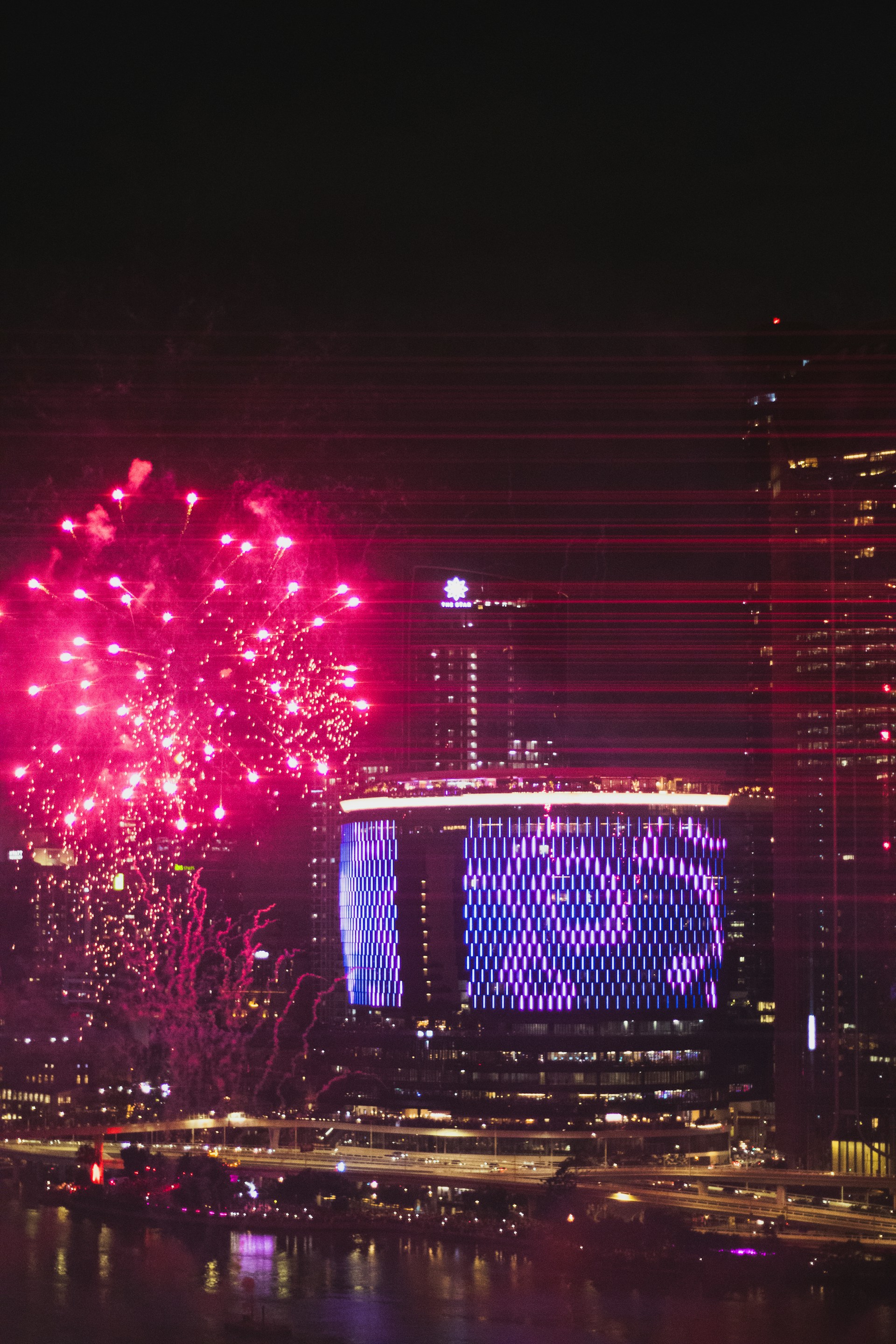 Fireworks explode over a city skyline at night.