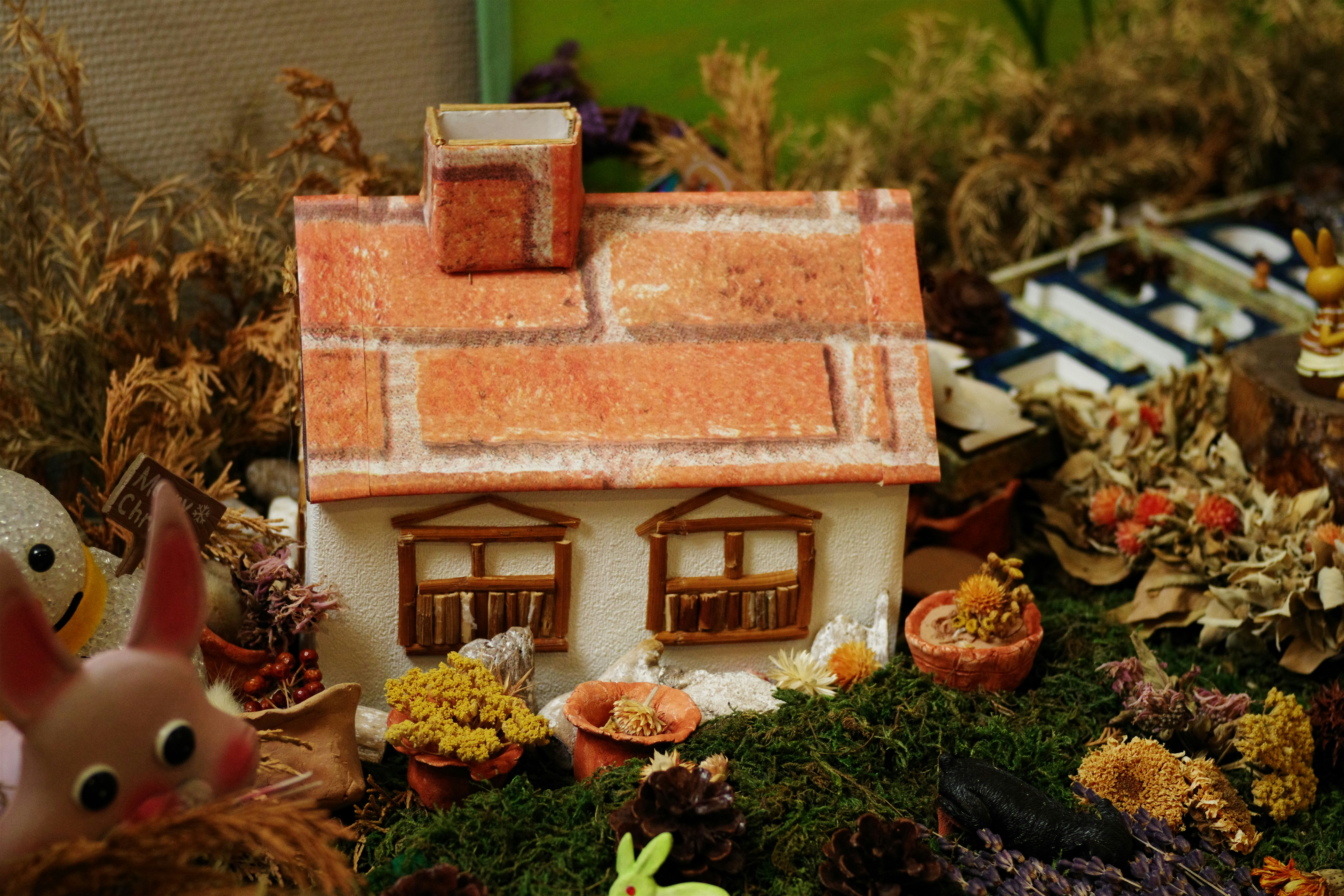 Casa en miniatura con techo de ladrillo y decoraciones de jardín