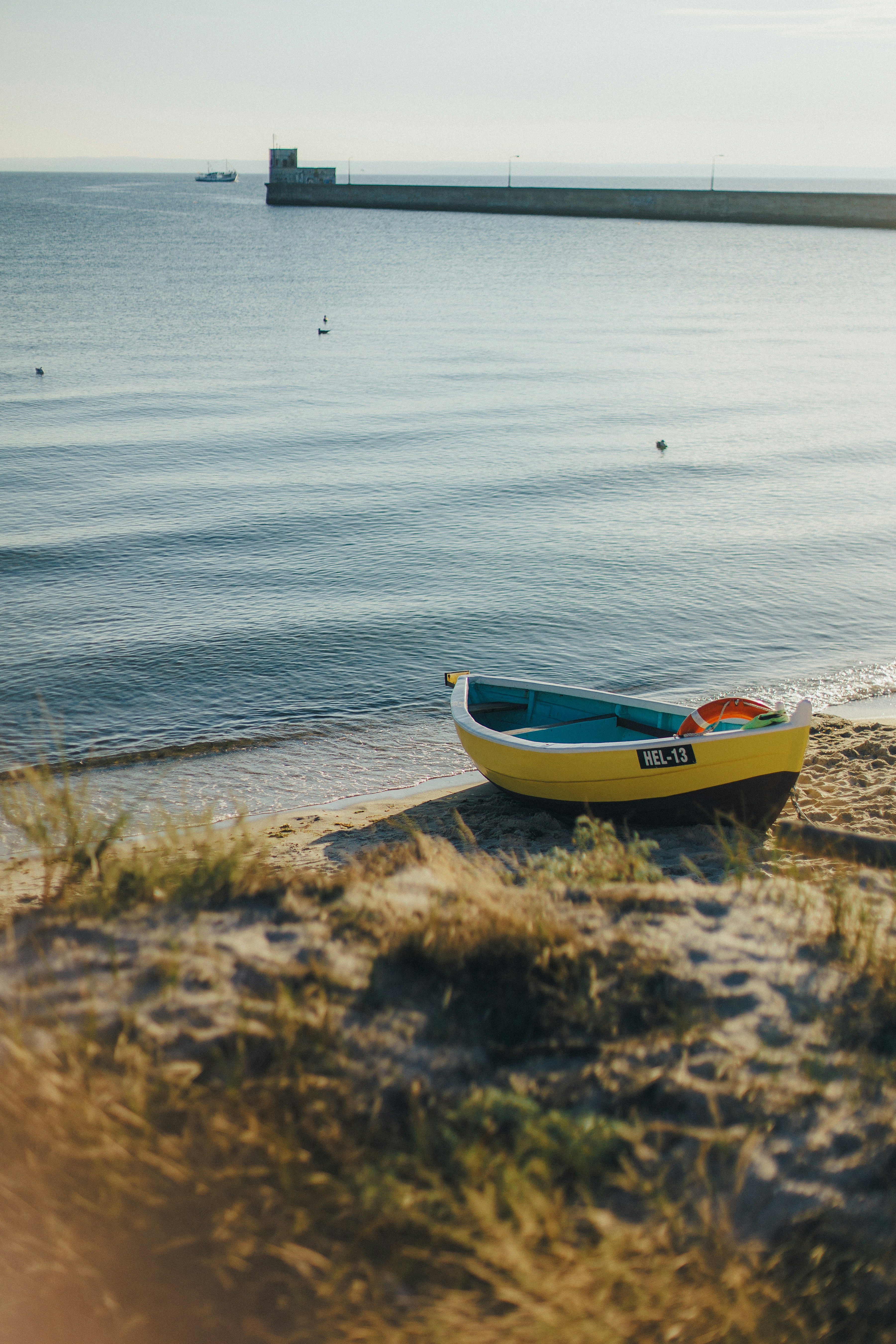 Yellow rowboat resting on a sandy beach near the ocean.