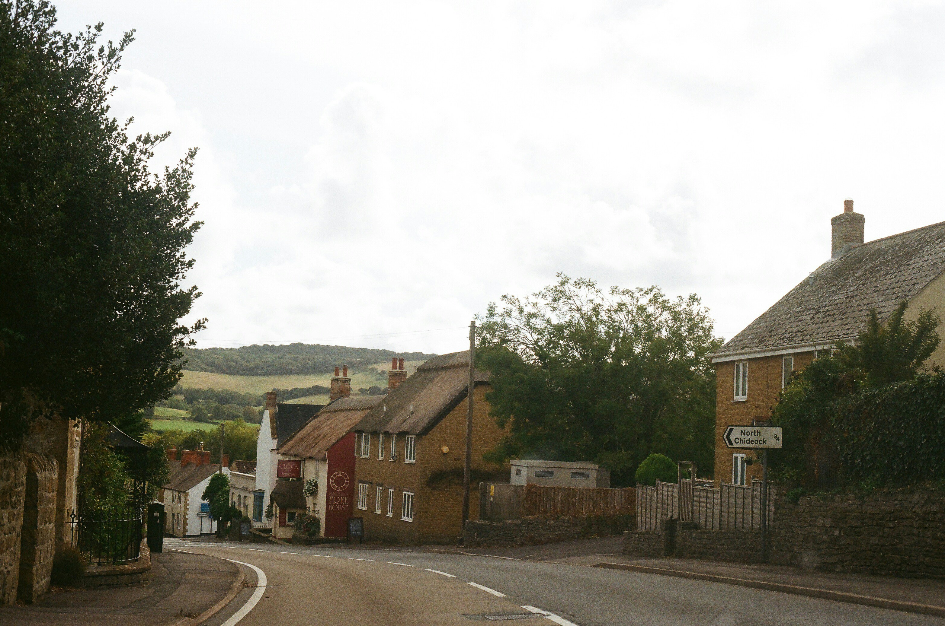 Stop image for Selkirk Loop: A 2-Day Motorcycle & Camping Adventure from Kaslo - Road curving through a village with houses and hills. -  in Kootenay Rockies, British Columbia, Canada - Photo by Tanya Barrow on Unsplash