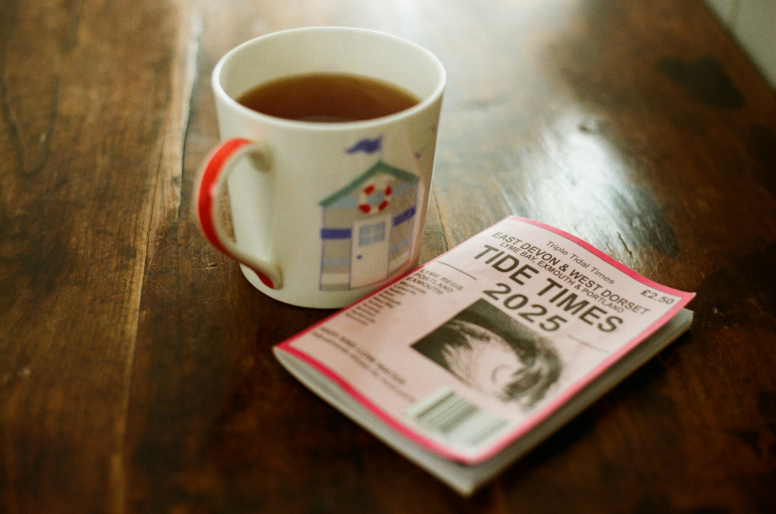 Uma caneca de chá ao lado de um livreto de horários de maré