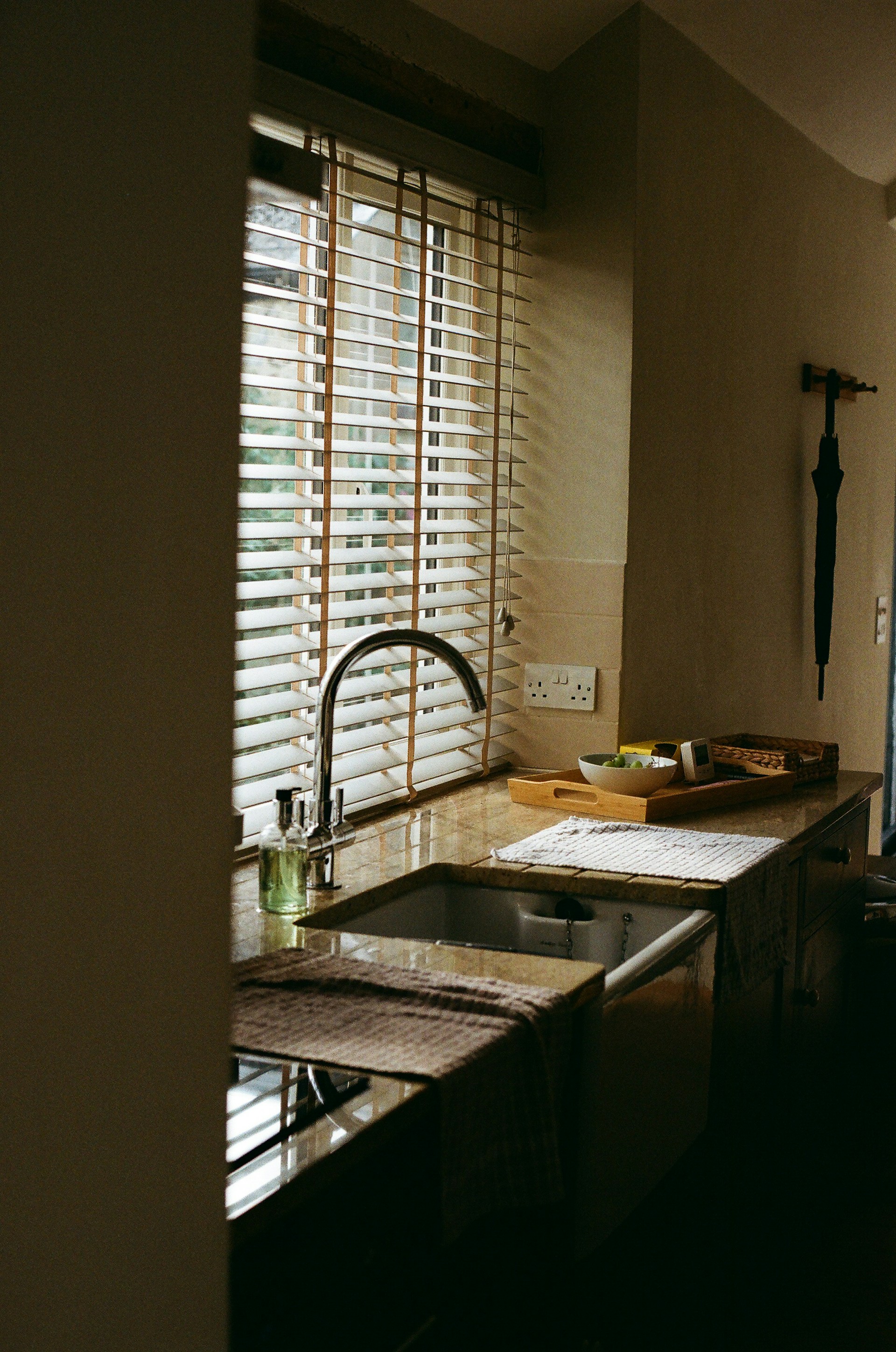 Kitchen sink with blinds and tray.