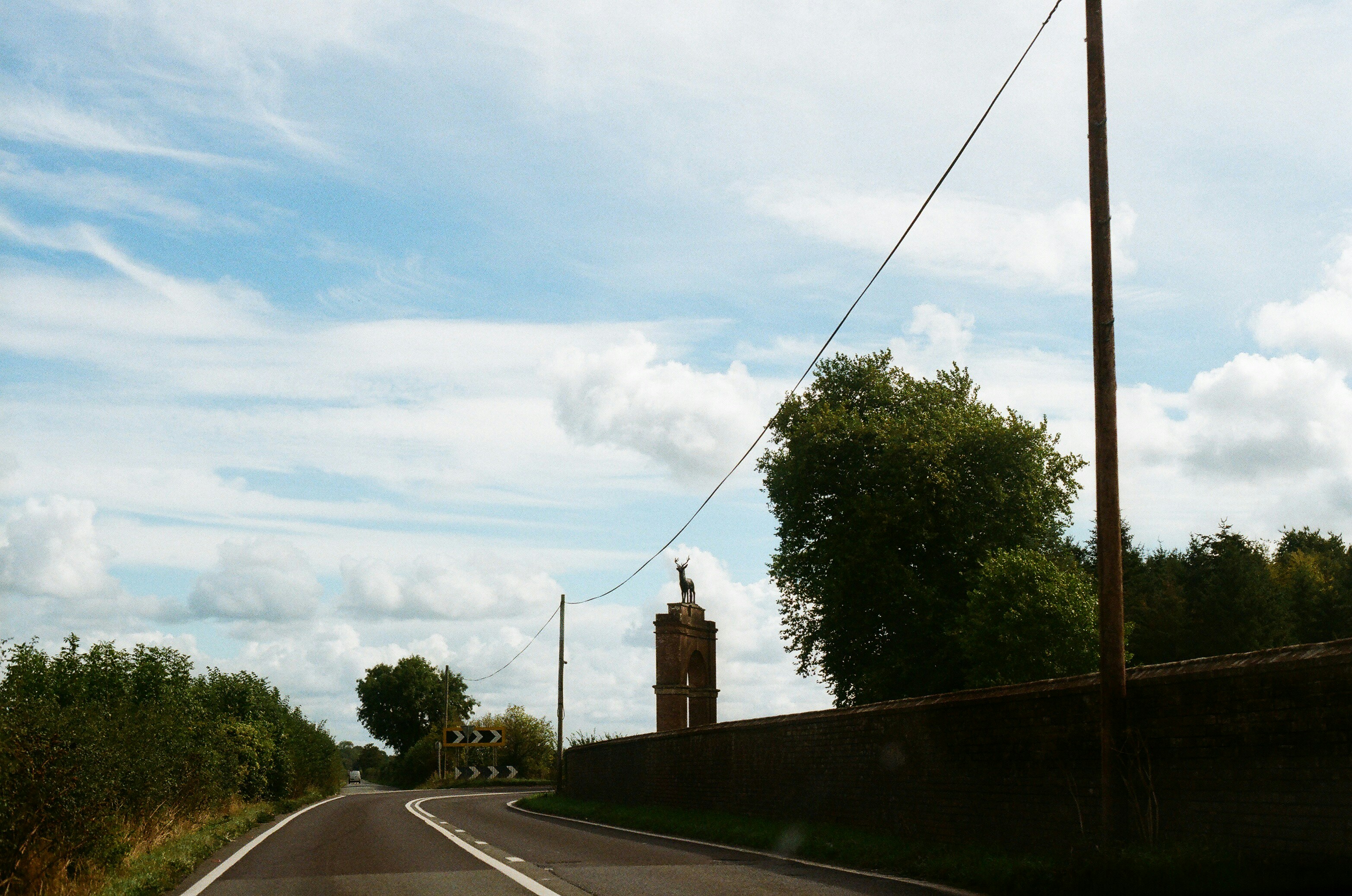 Road leading to a tower with trees and sky.