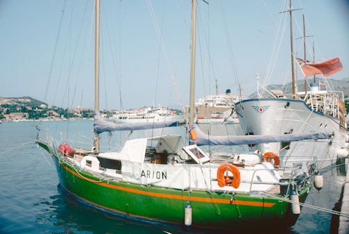 Green sailboat named arion docked in harbor