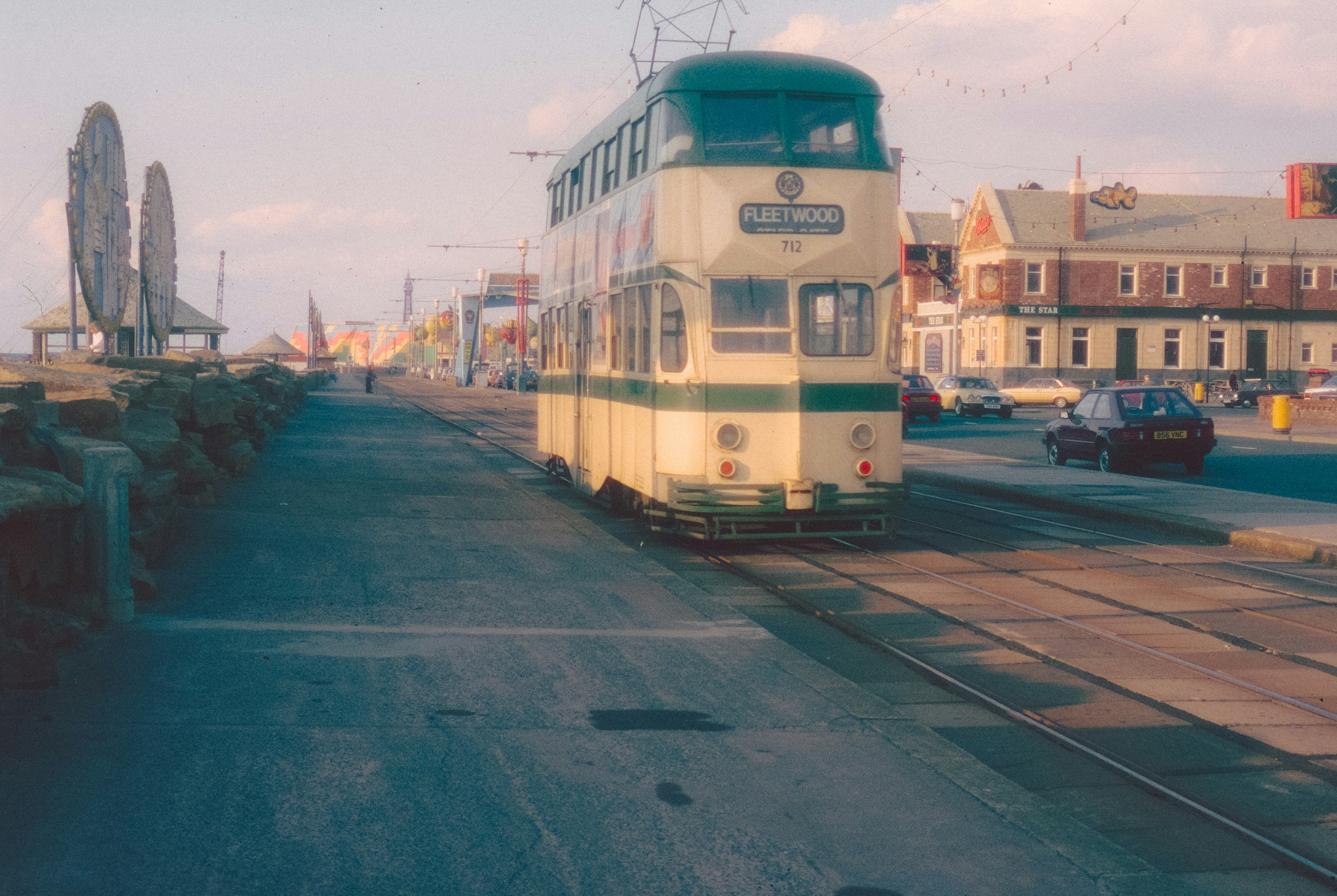 A vintage tram travels along a coastal road