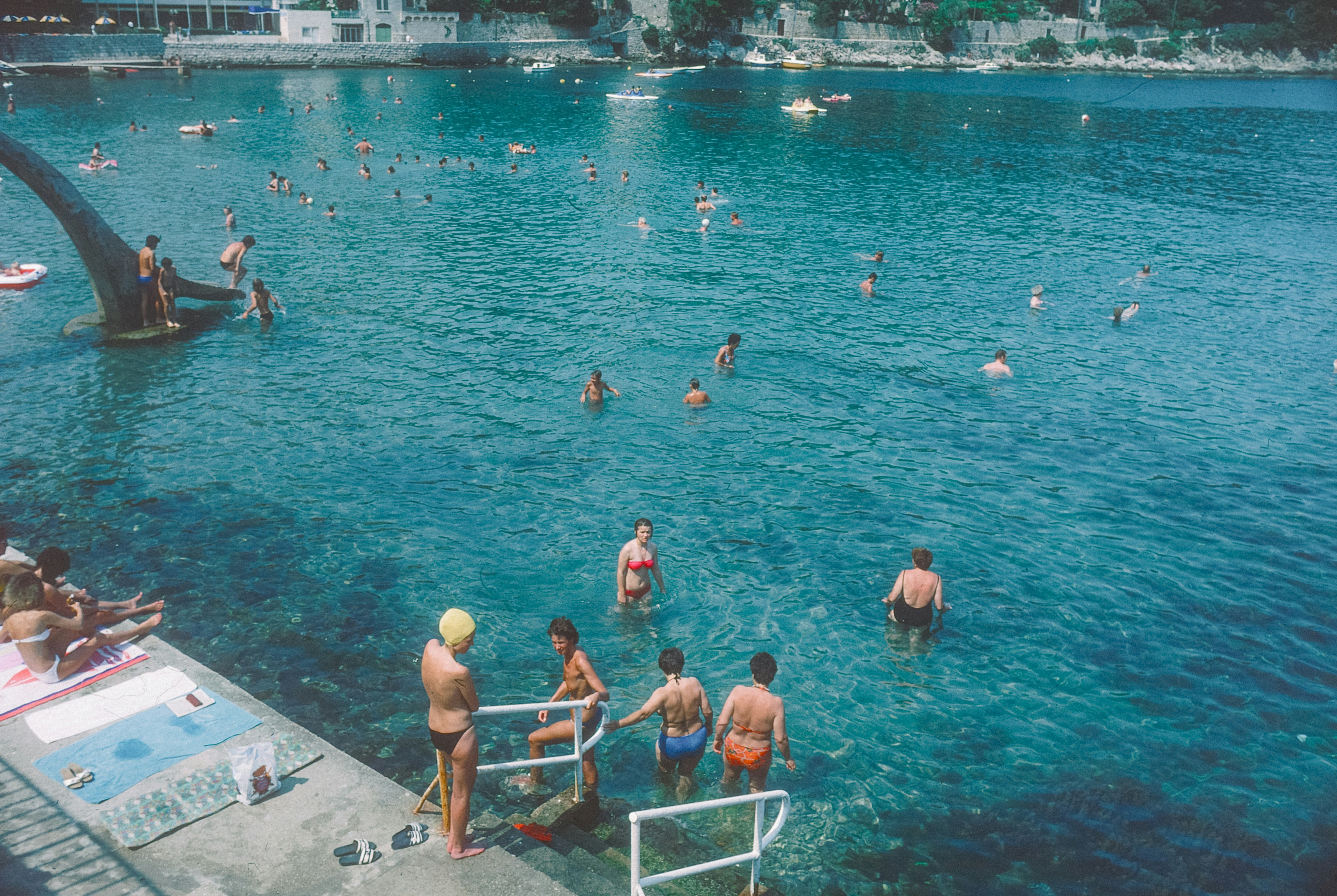 People swimming and relaxing by the clear blue water.