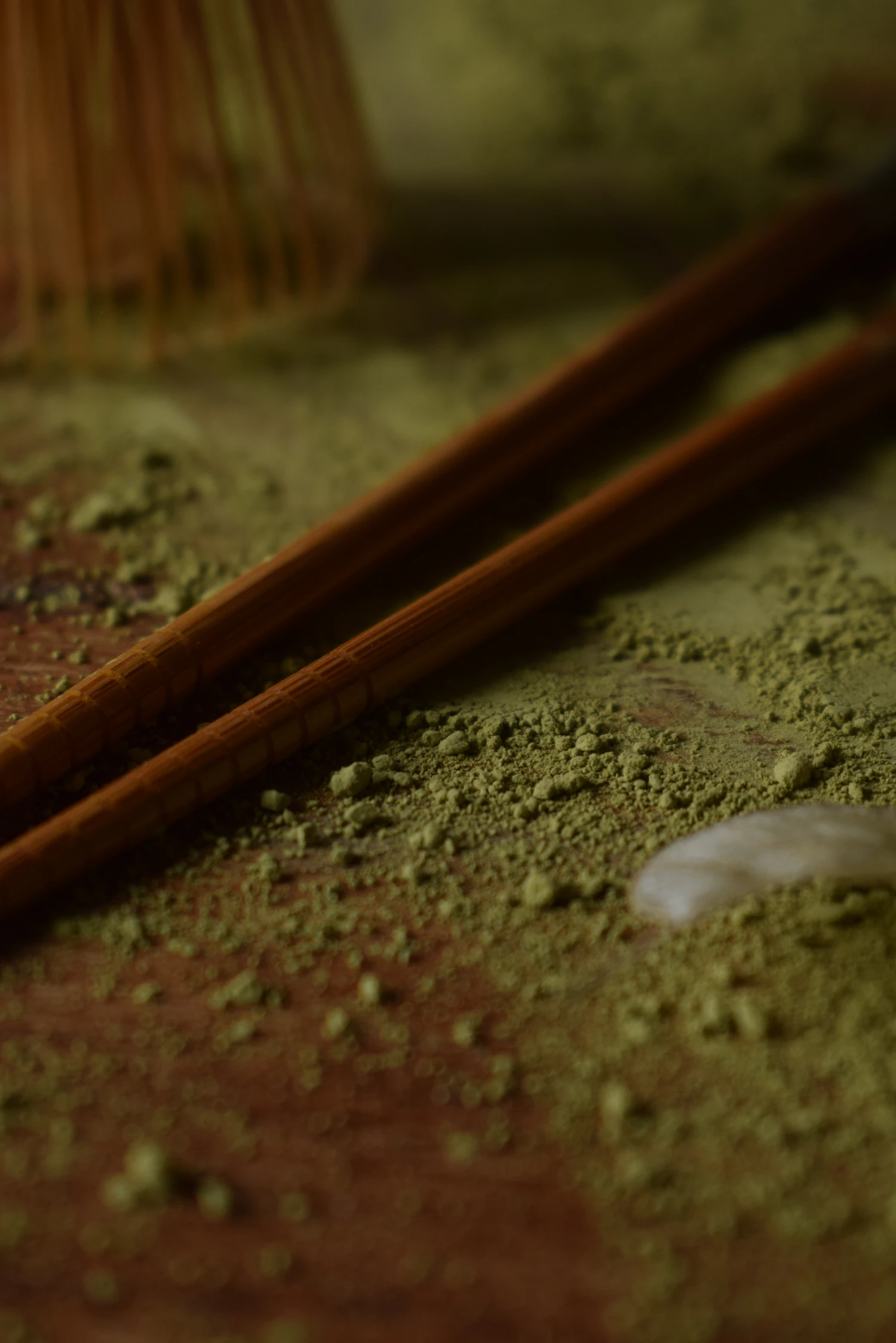 Vivid green matcha powder with a bamboo whisk on a wooden surface