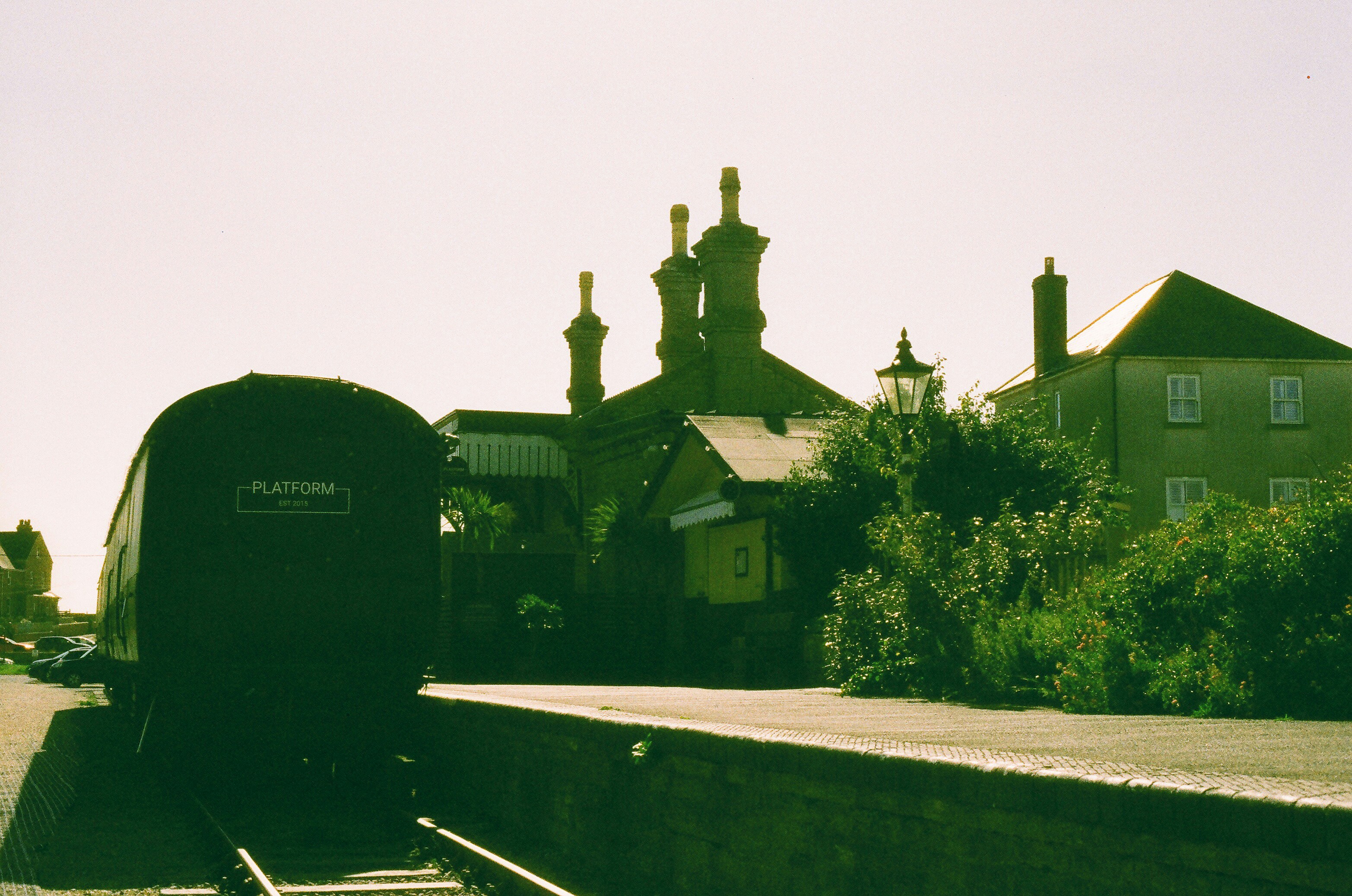 Train at a station with buildings and trees.