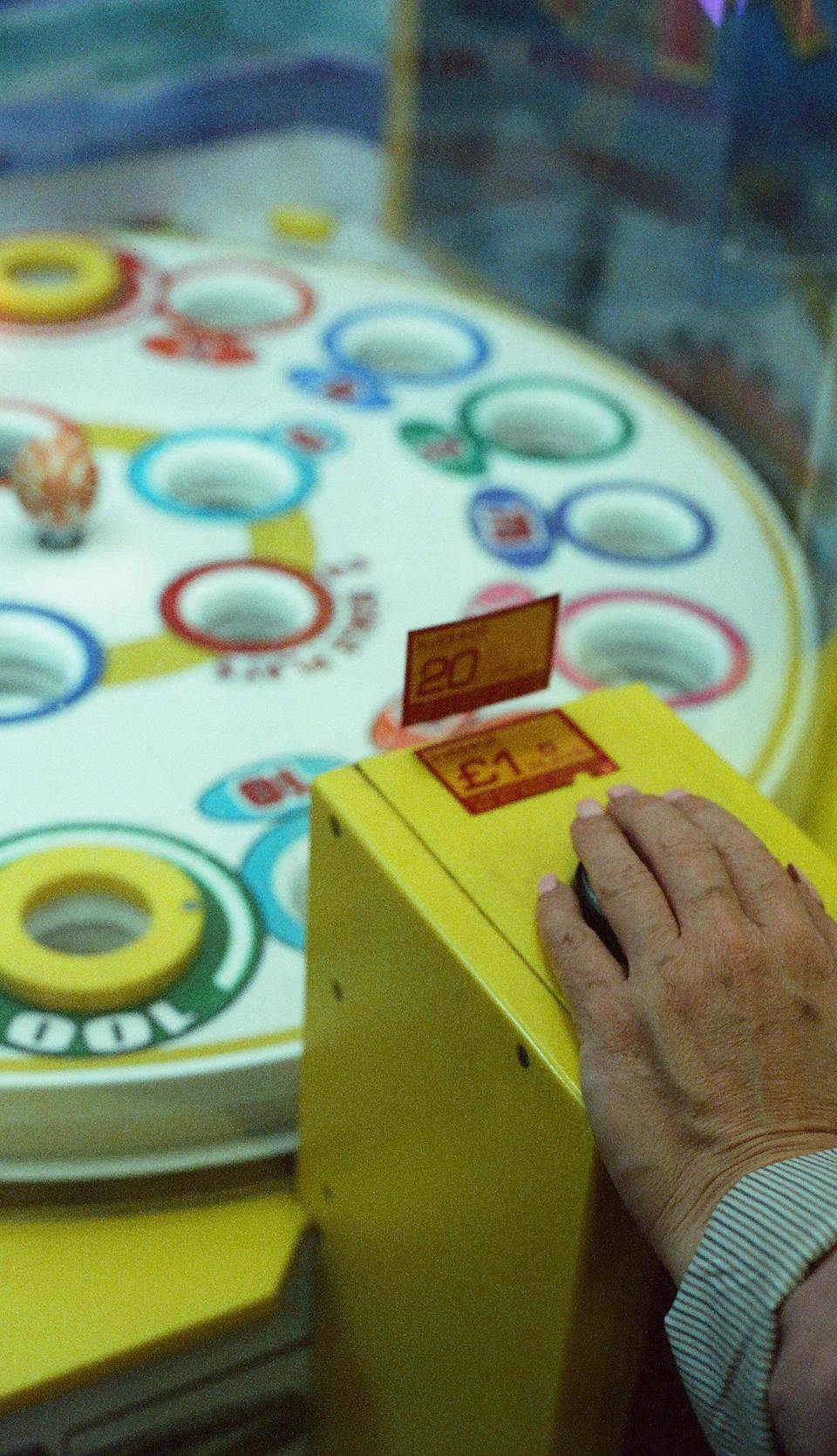 Person's hand reaches out to a yellow game machine with a red price tag