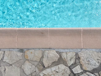 Clear blue water meets stone poolside edge of pool