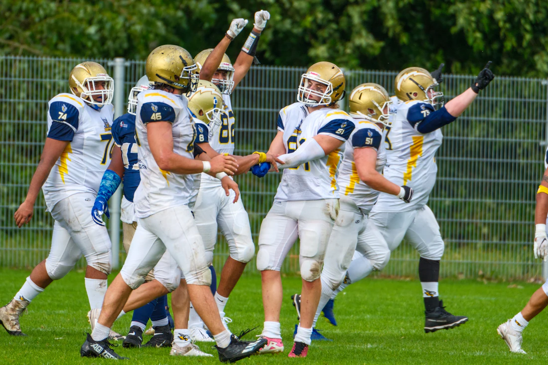 American football players celebrating on the field under stadium lights