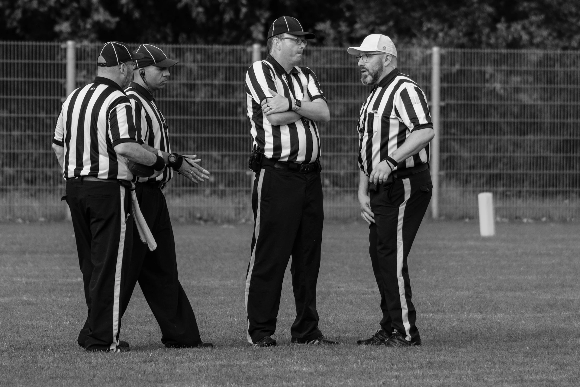 Four referees in striped shirts on a field
