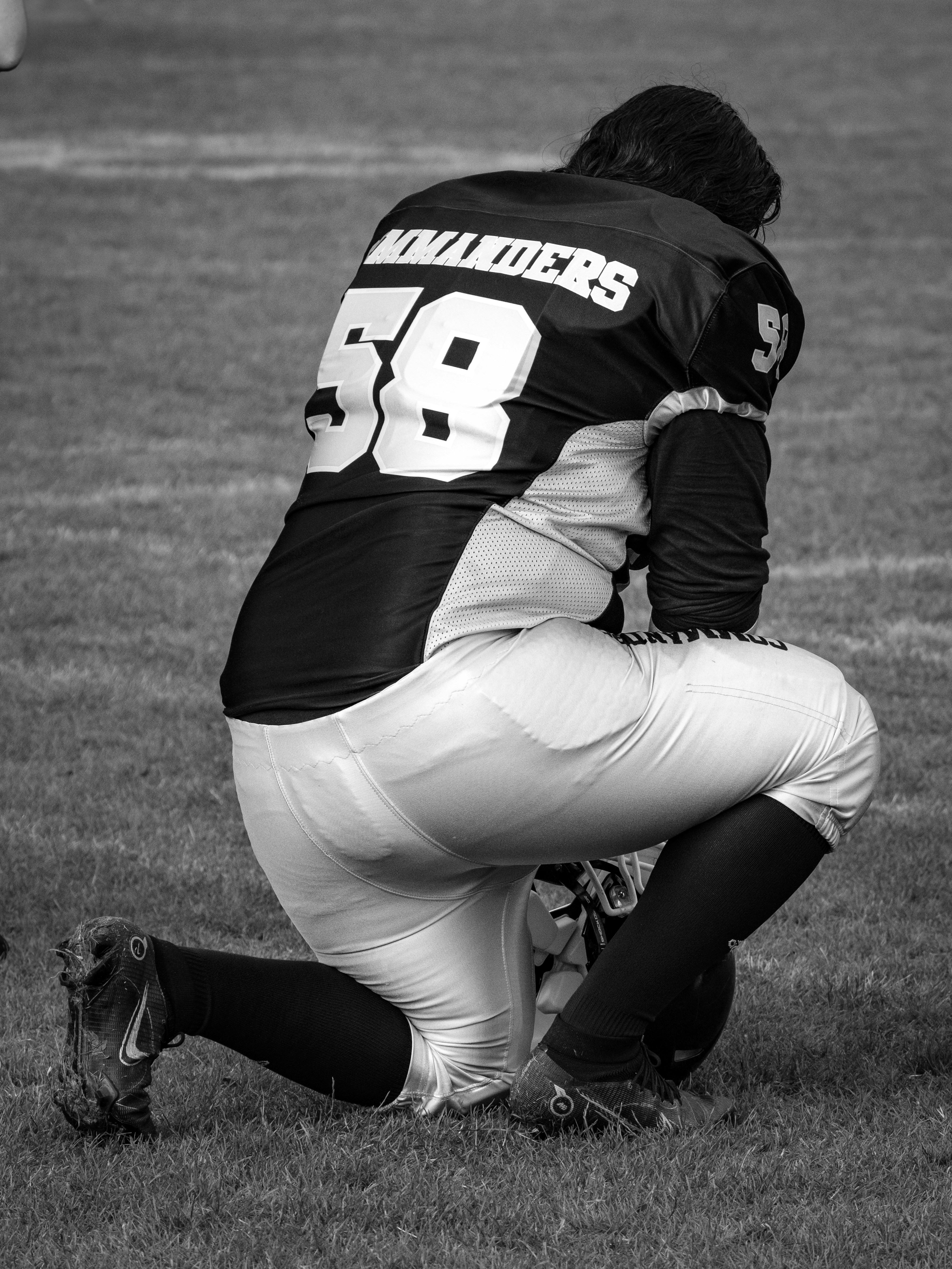 Football player kneeling on a grassy field.