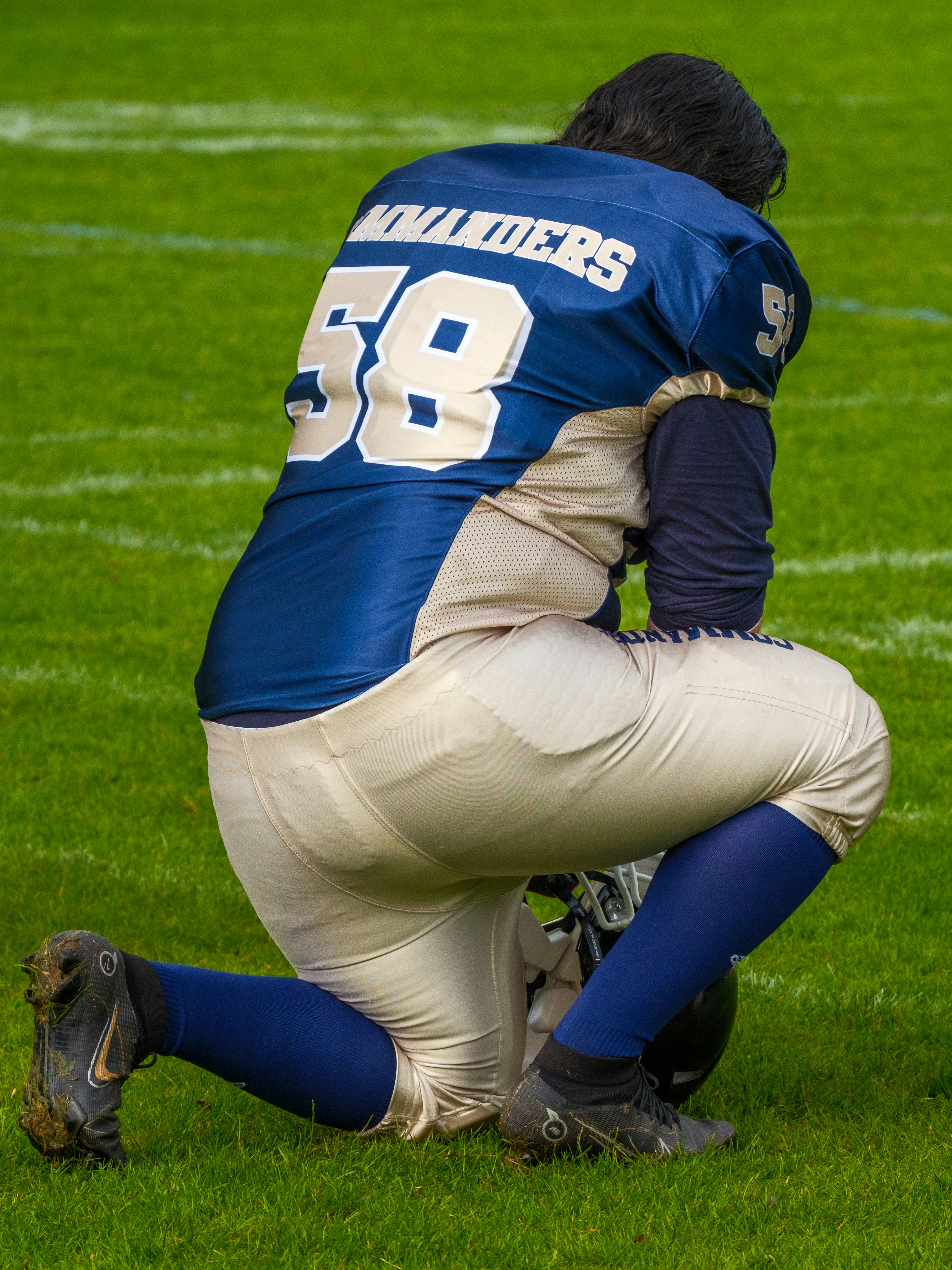American football player kneeling on a green field.