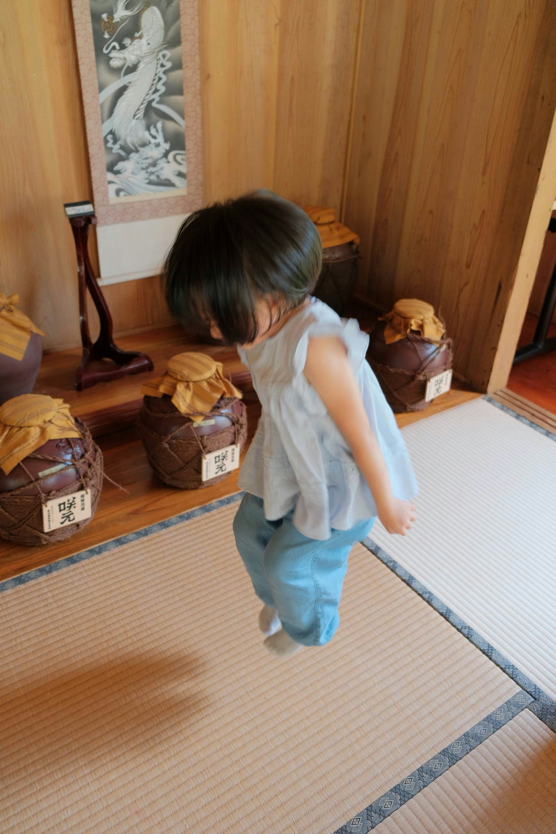 Young child jumping in a room with jars
